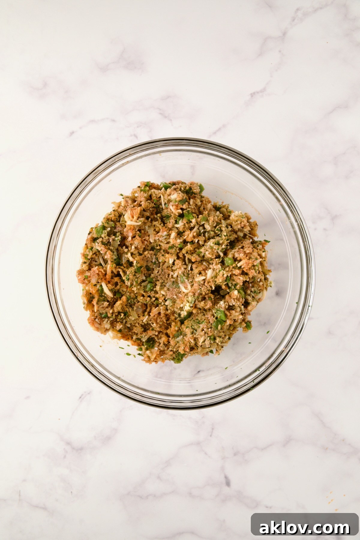 Ingredients for meatloaf mixed together in a glass bowl before ground meats are added.