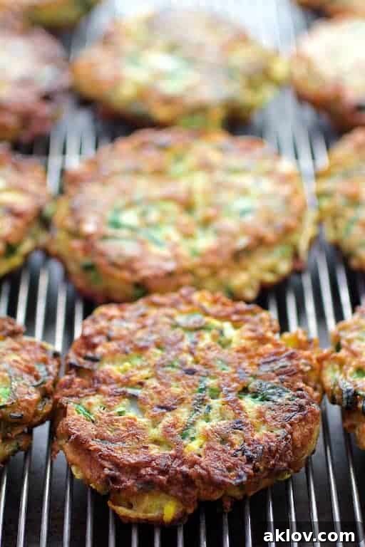 Firecracker Zucchini Fritters with Cool Cilantro Lime Sour Cream 4 Freshly fried zucchini fritters cooling on a metal wire rack, allowing excess oil to drip away and maintain their crispness.