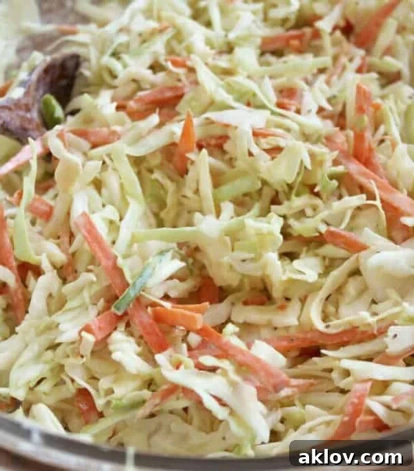 Coleslaw being mixed with serving utensils.
