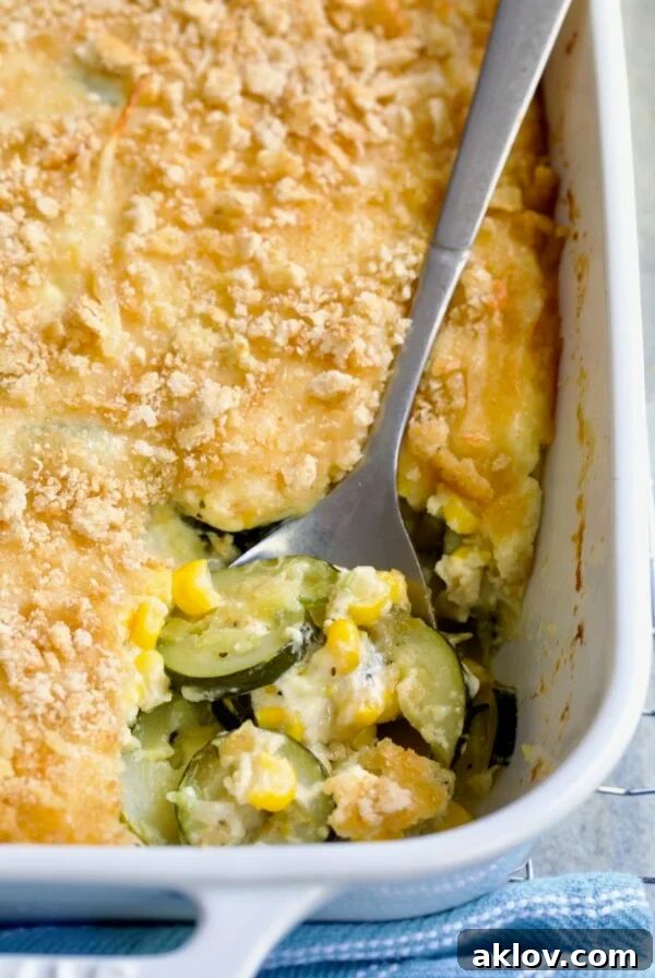 Zucchini Corn Casserole in white rectangular baking dish with serving spoon scooping some out.