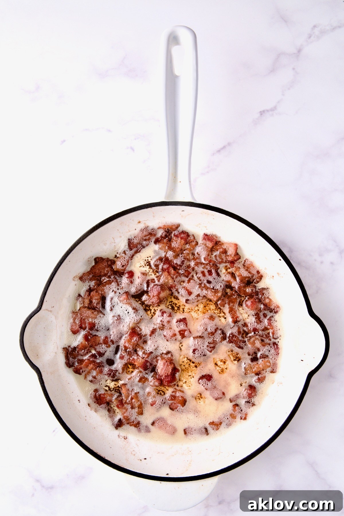 Cooked bacon in white enamel cast iron skillet.