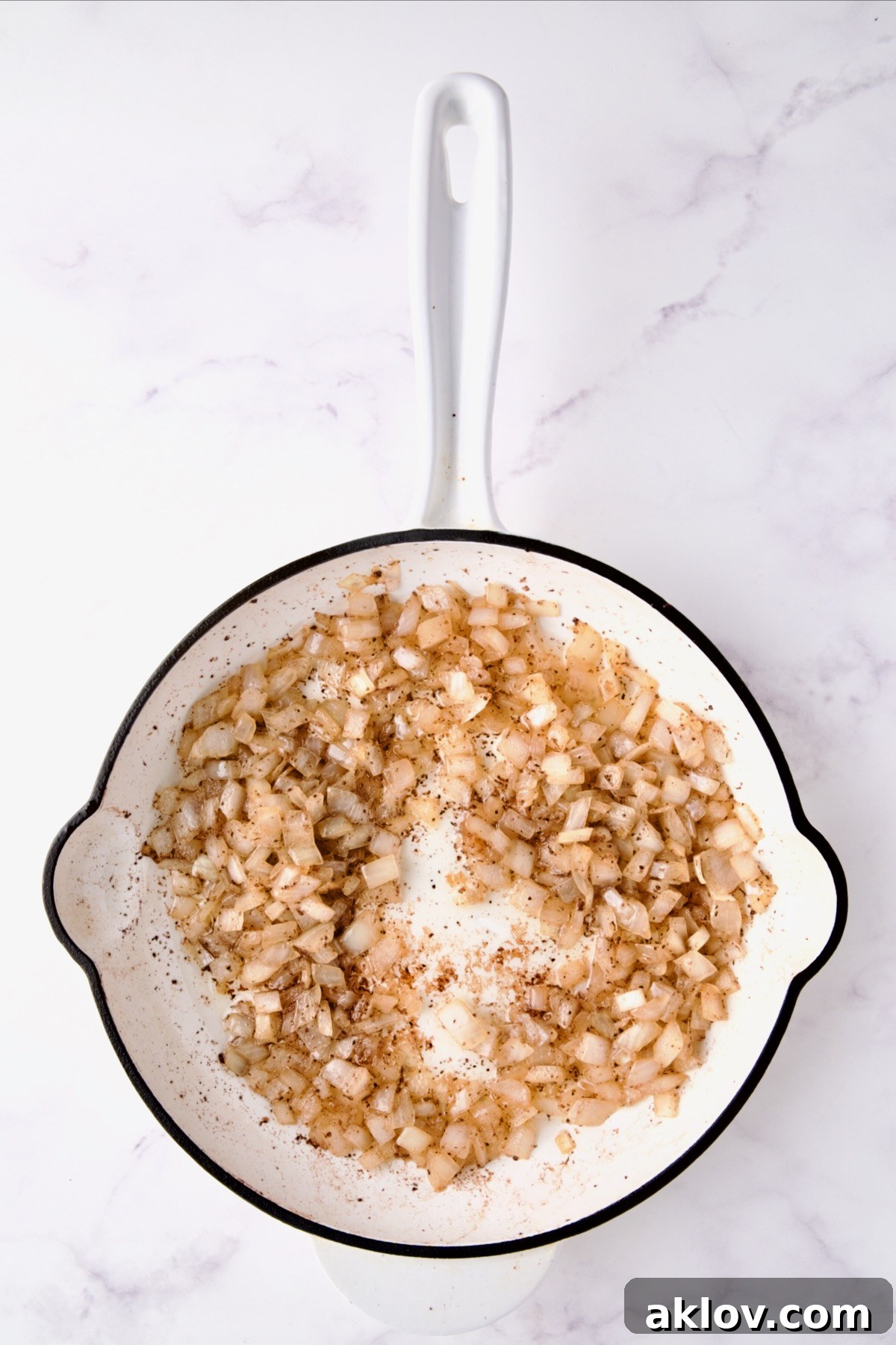 Cooked onions in white enamel cast iron skillet.