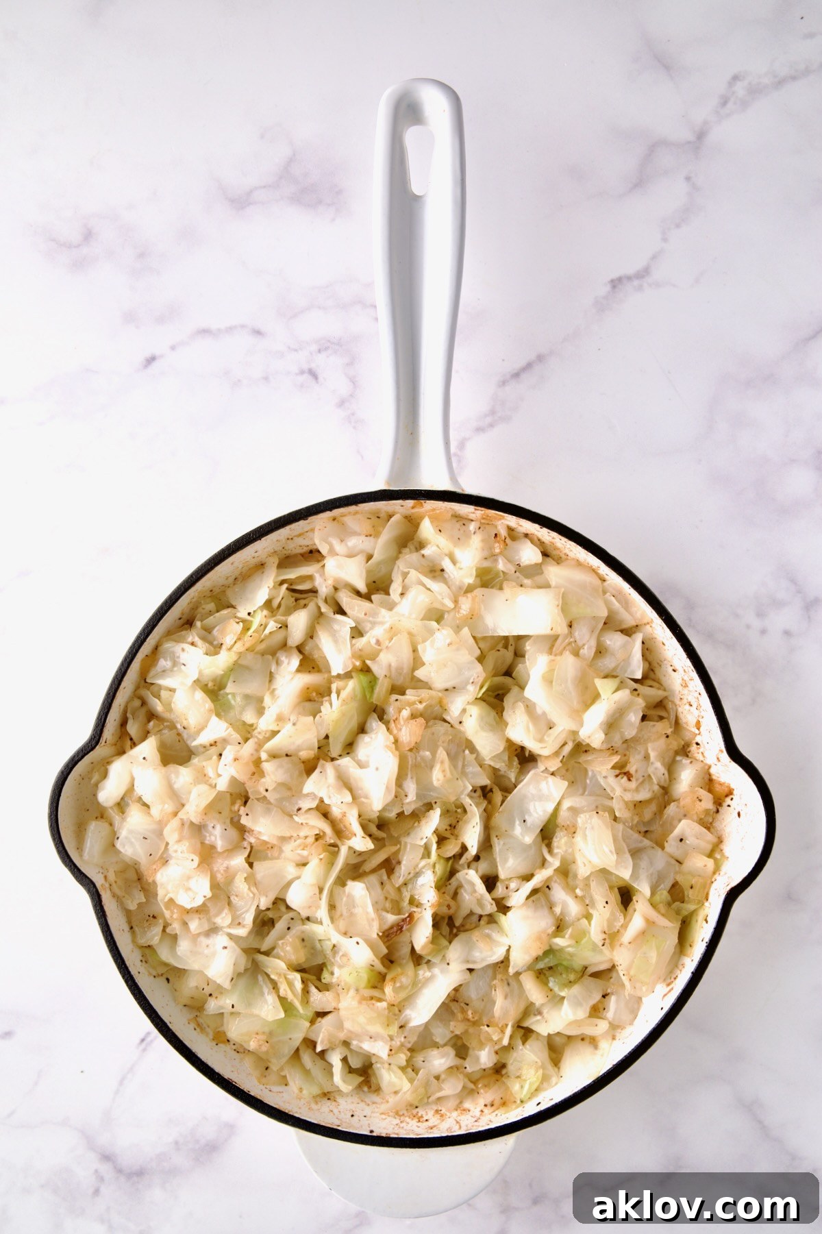 Lightly cooked cabbage in white enamel cast iron skillet.