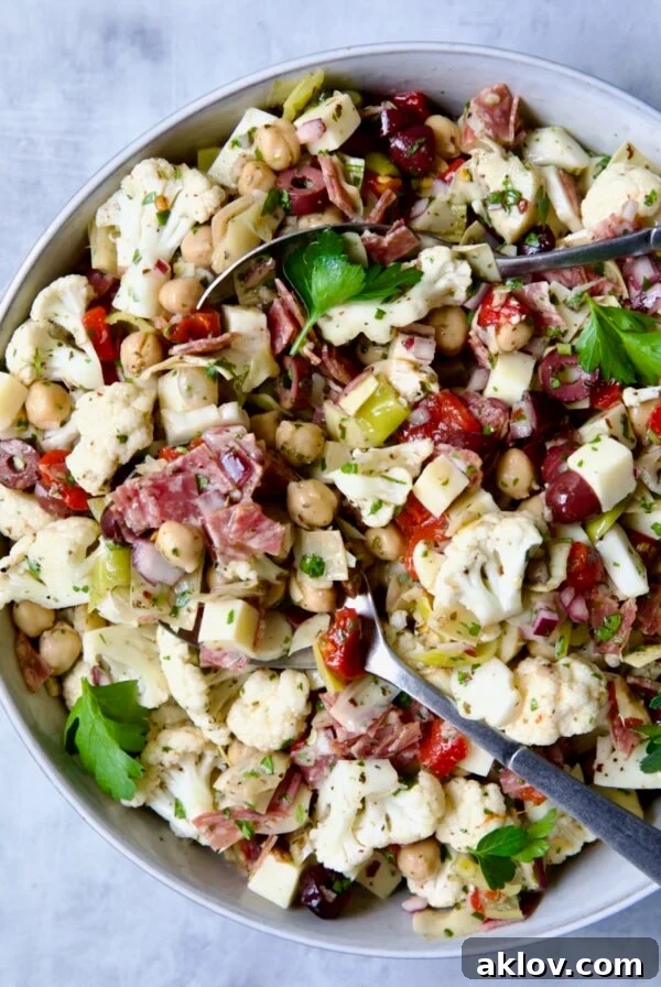 Cauliflower Antipasto Salad in serving bowl with serving utensils, light, refreshing, and reminiscent of a classic Italian appetizer.