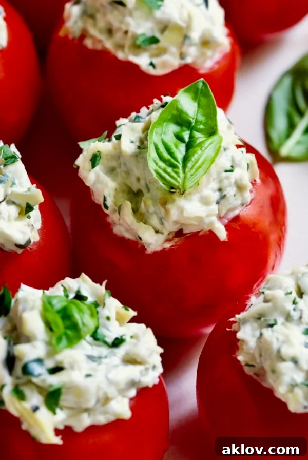 Cream Cheese and Artichoke Stuffed Tomatoes garnished with fresh basil leaves, an elegant and easy appetizer.