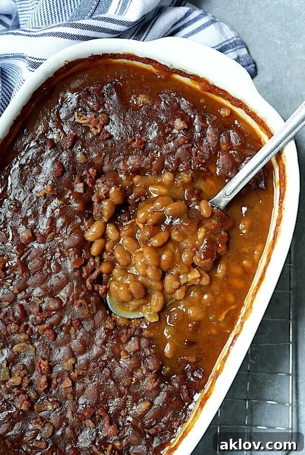 Kicked Up Canned Baked Beans - Overhead shot of the baked beans in white baking dish, an easy and delicious crowd-pleaser.
