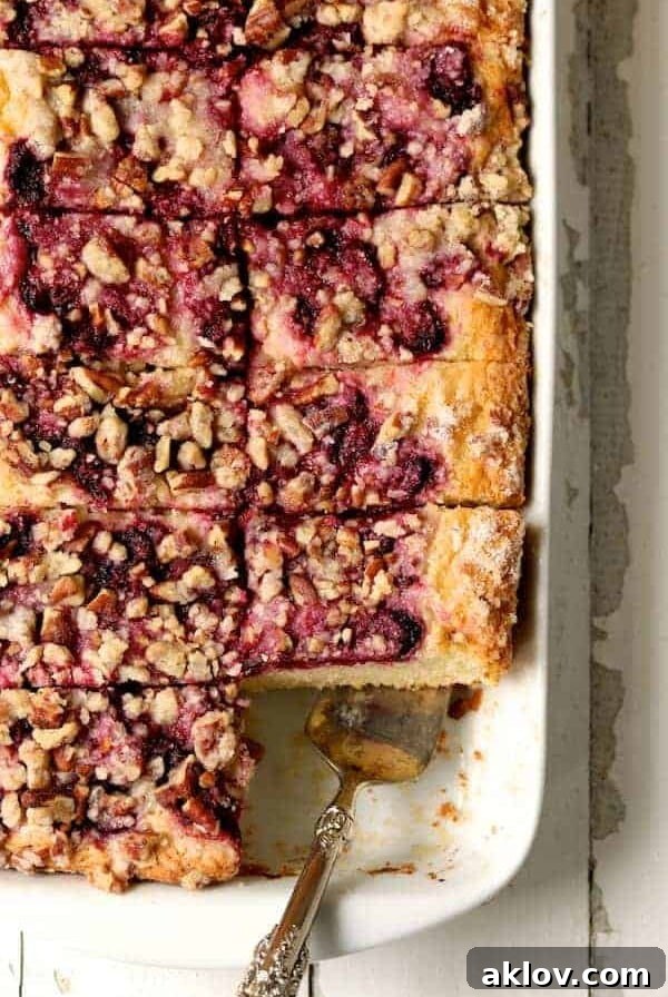Easy Raspberry Coffee Cake in white rectangular baking pan, cut into pieces with silver server, an award-winning recipe.