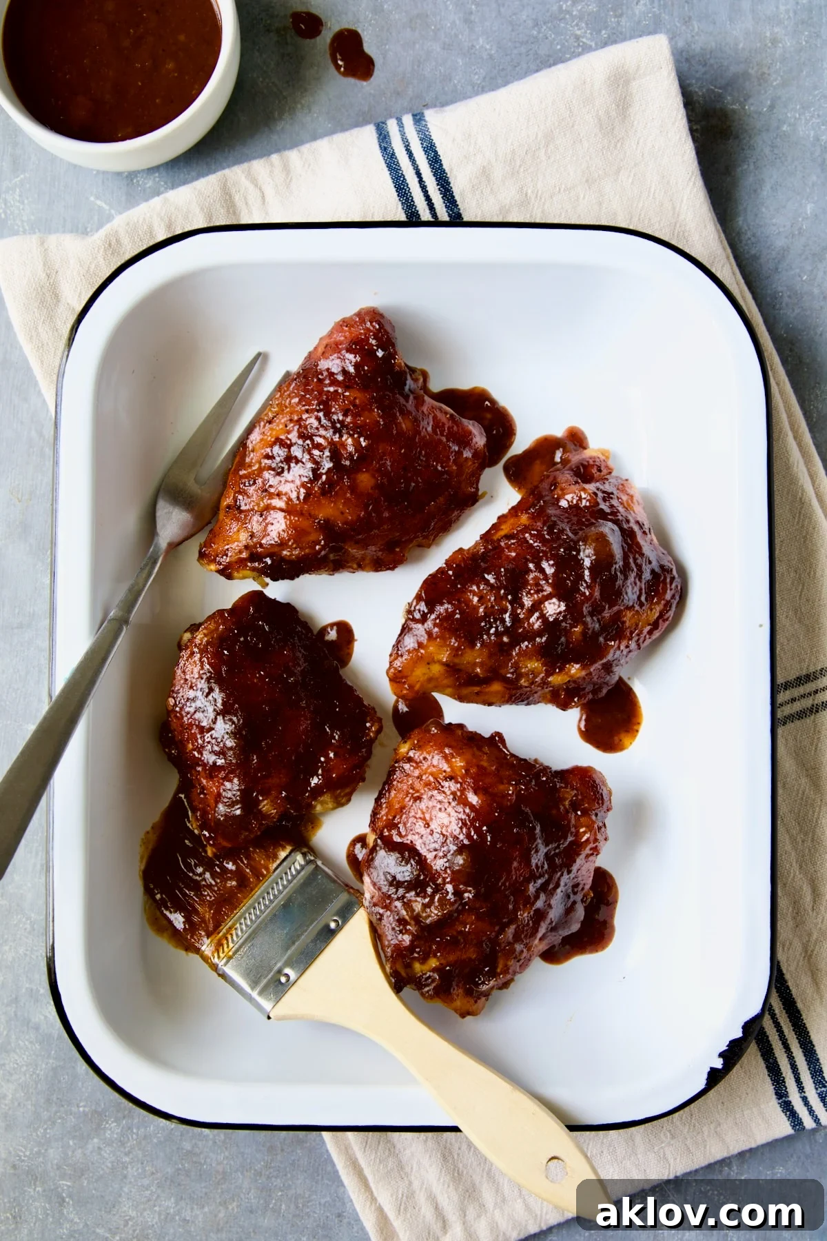 Four Baked BBQ Chicken Thighs in white enamel serving dish.