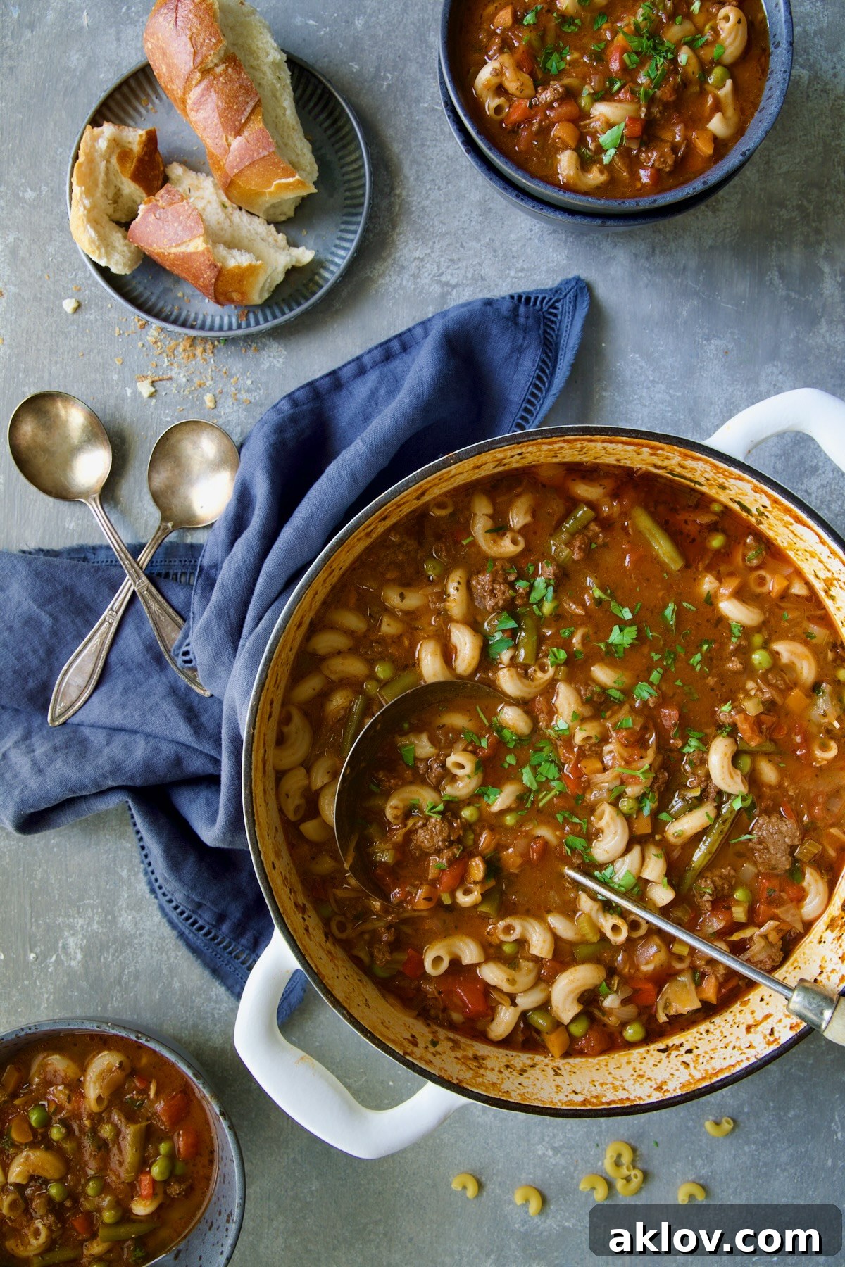 Hamburger Vegetable Soup in a white Dutch oven with two bowls ready for serving.