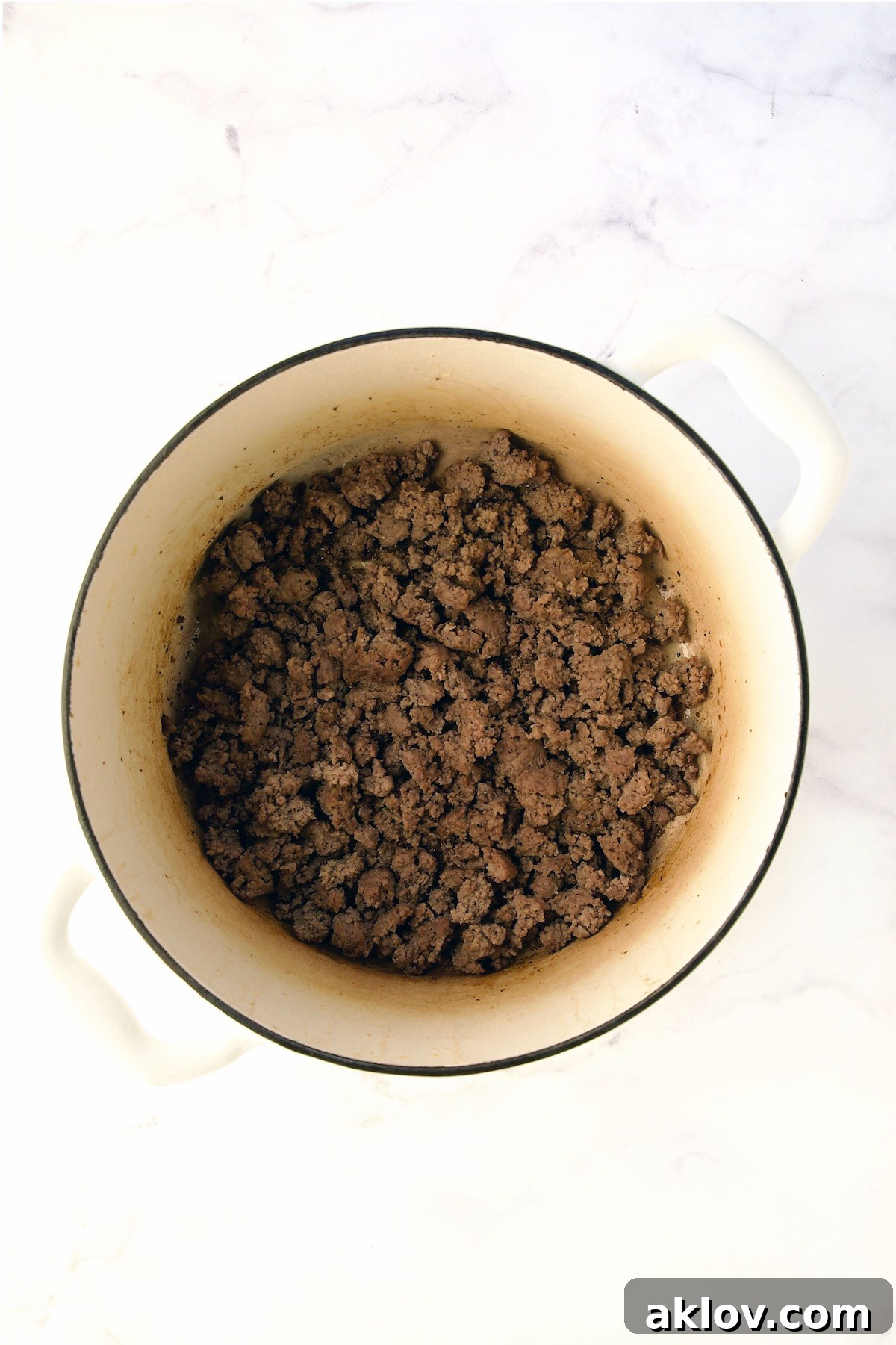 Perfectly cooked ground beef in a white Dutch oven, ready to be removed.
