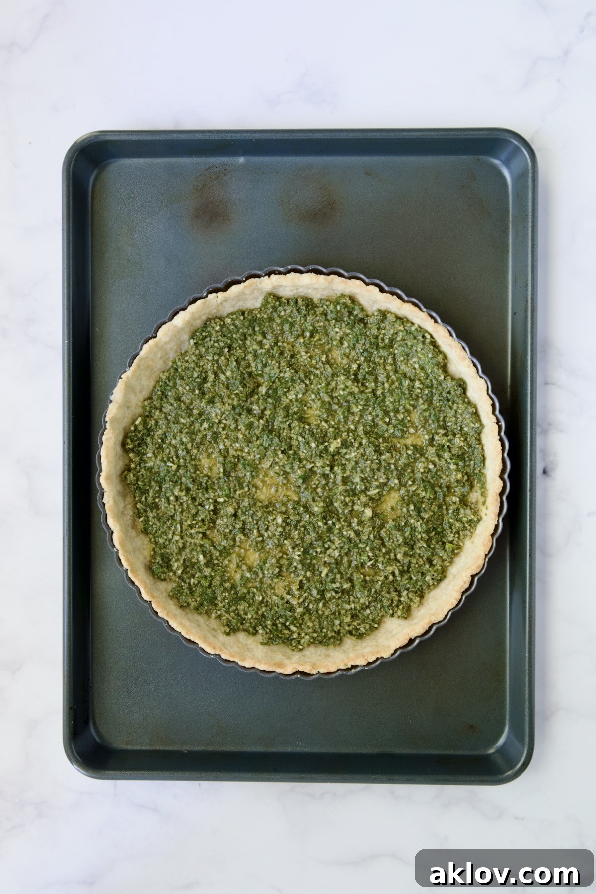 Pesto spread over bottom of tart crust.