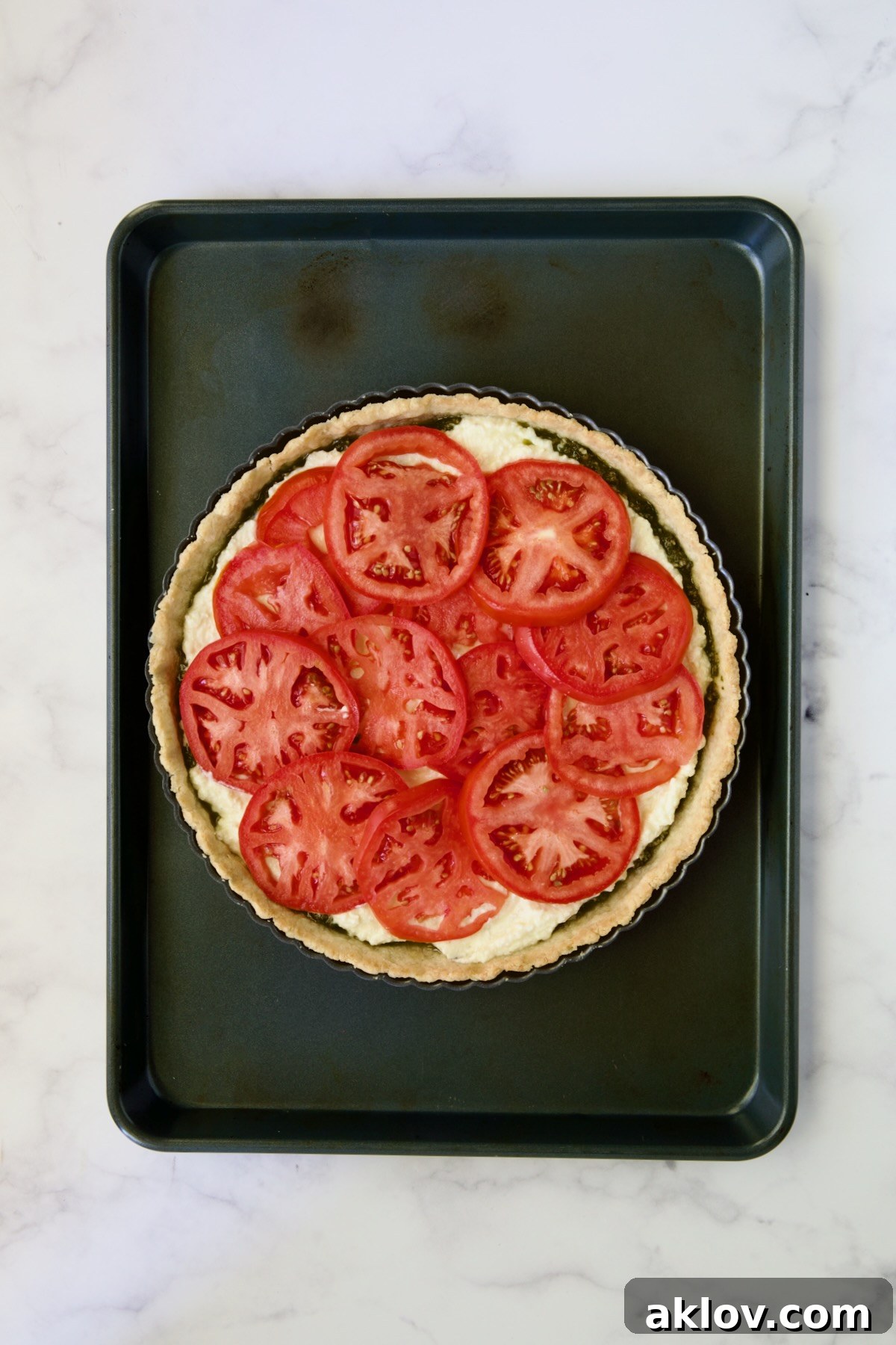 Tomatoes placed over ricotta and pesto in tart pan.
