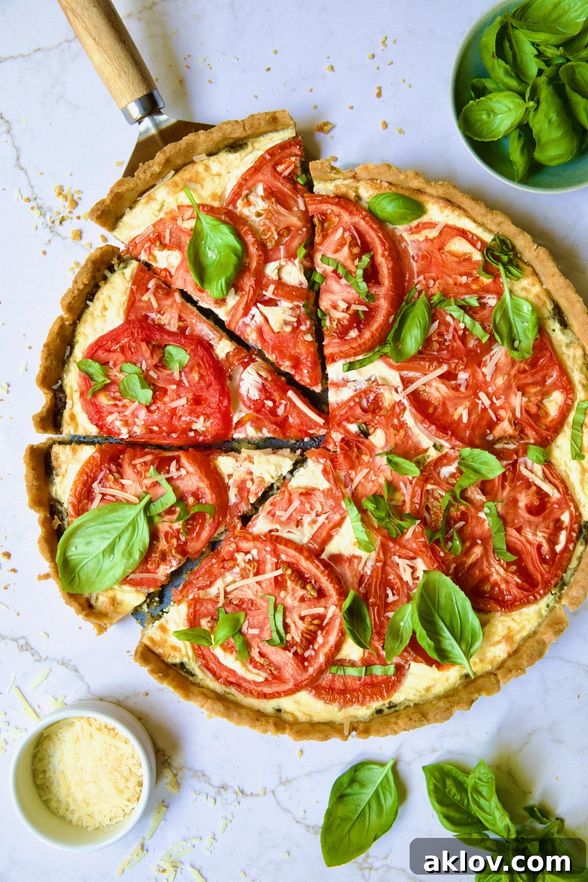 Tomato Tart with Ricotta and Cheese garnished with fresh basil leaves cut into wedges with pie server picking up a piece.