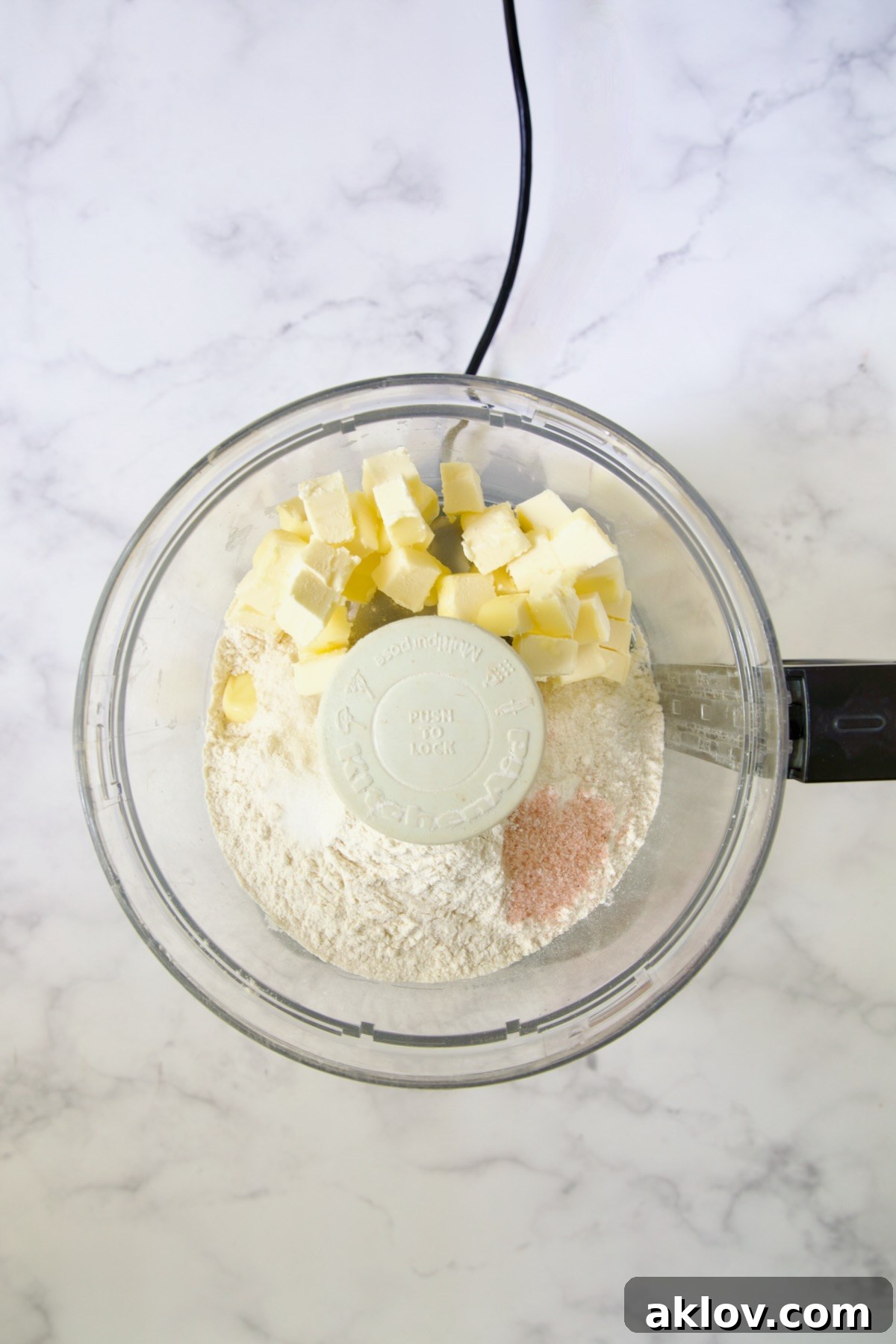 Butter cubes, flour, salt and pepper in bowl of food processor.
