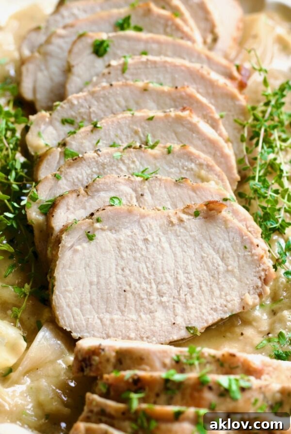Succulent Braised Pork Loin in Dijon Mustard Sauce, artfully garnished with fresh thyme sprigs, promising a flavorful meal.