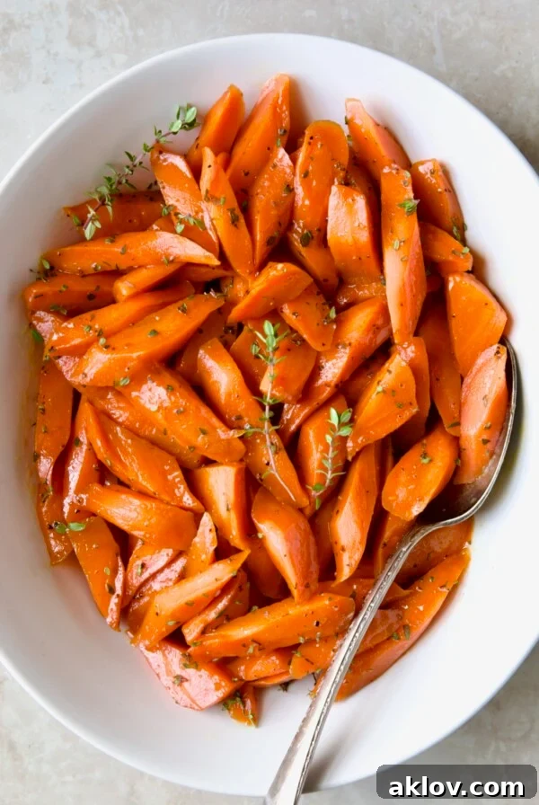 Delicious Bourbon-Glazed Carrots with Honey, served in a white bowl and garnished with fresh thyme.