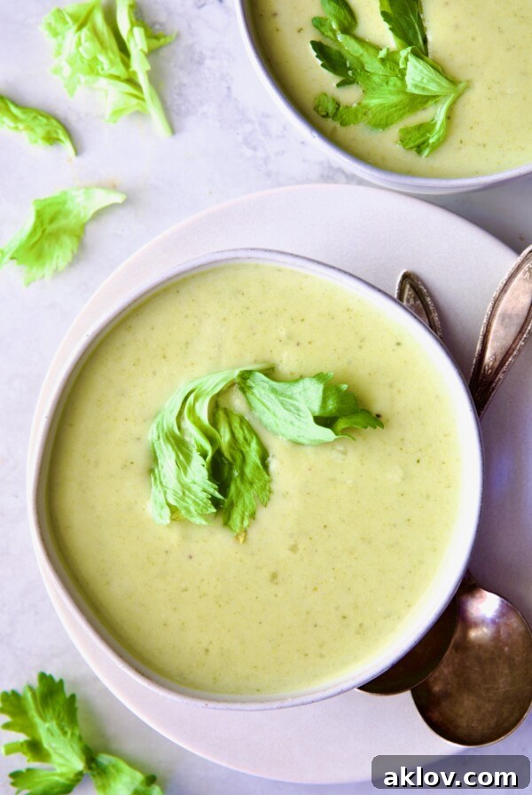 A delicate bowl of Cream of Celery Leaves Soup, perfectly plated on a white dish with elegant antique spoons, ready to be served.