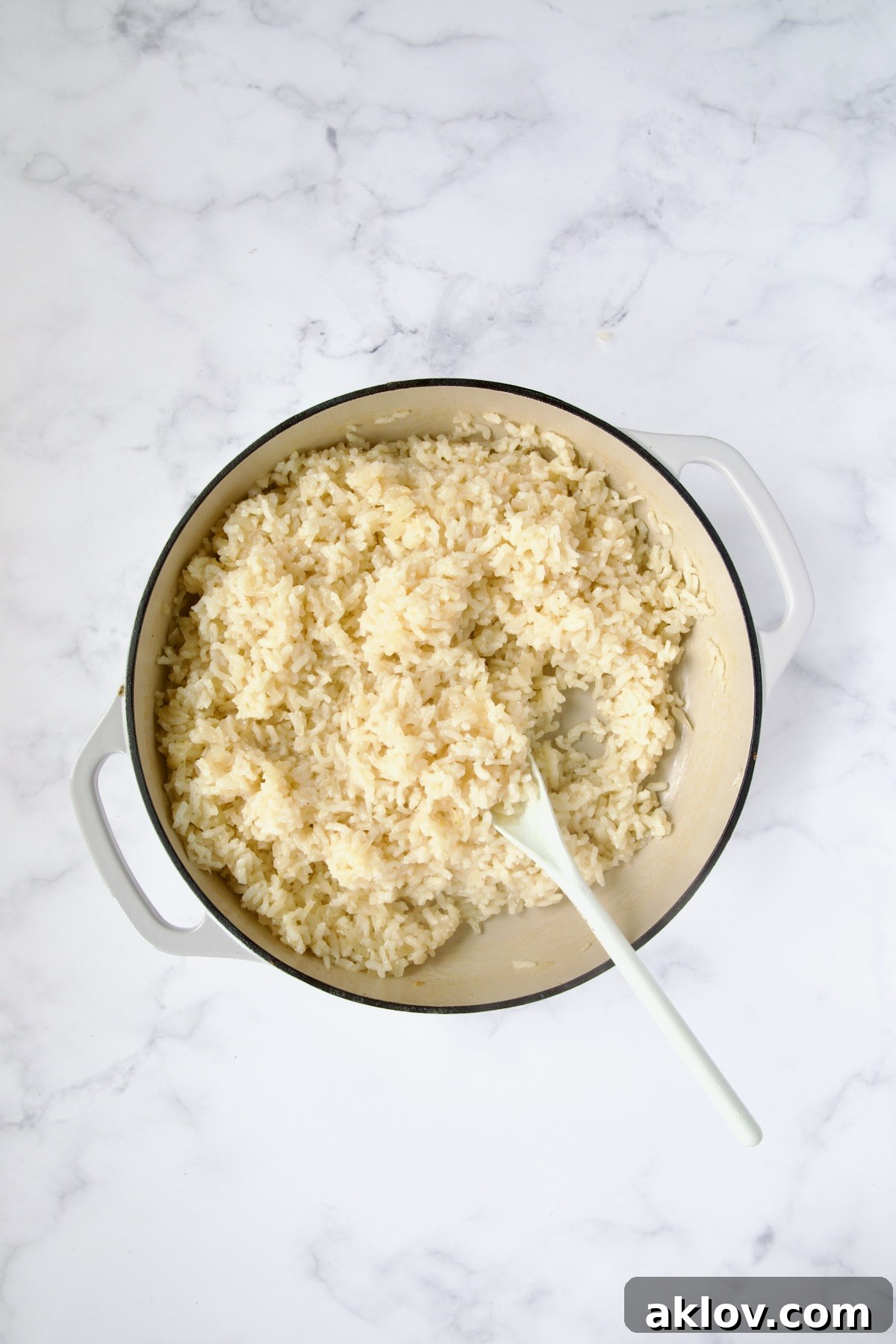 Cooked risotto in white enamel cast iron skillet.