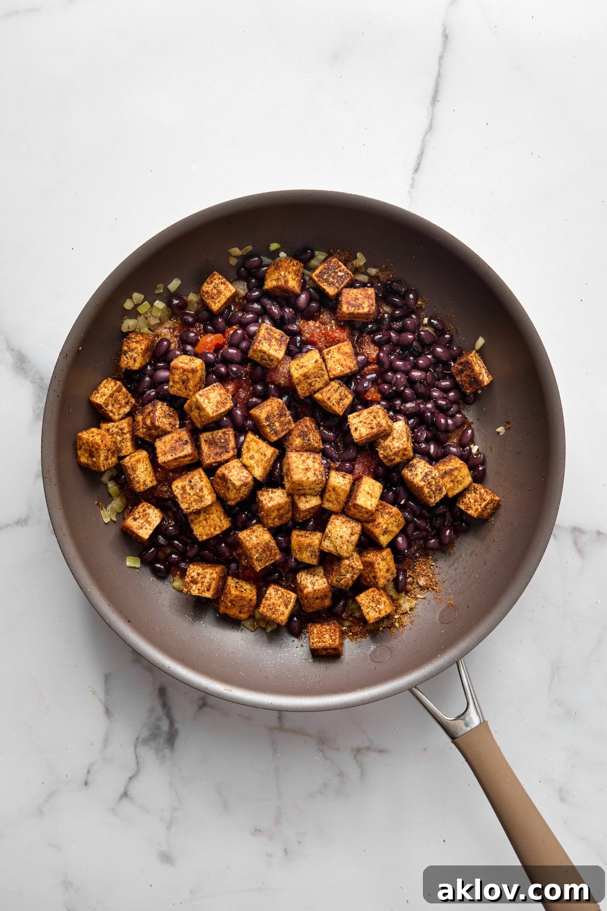 Seared tofu cubes and drained black beans integrated into the simmering tomato and onion mixture in the nonstick skillet.