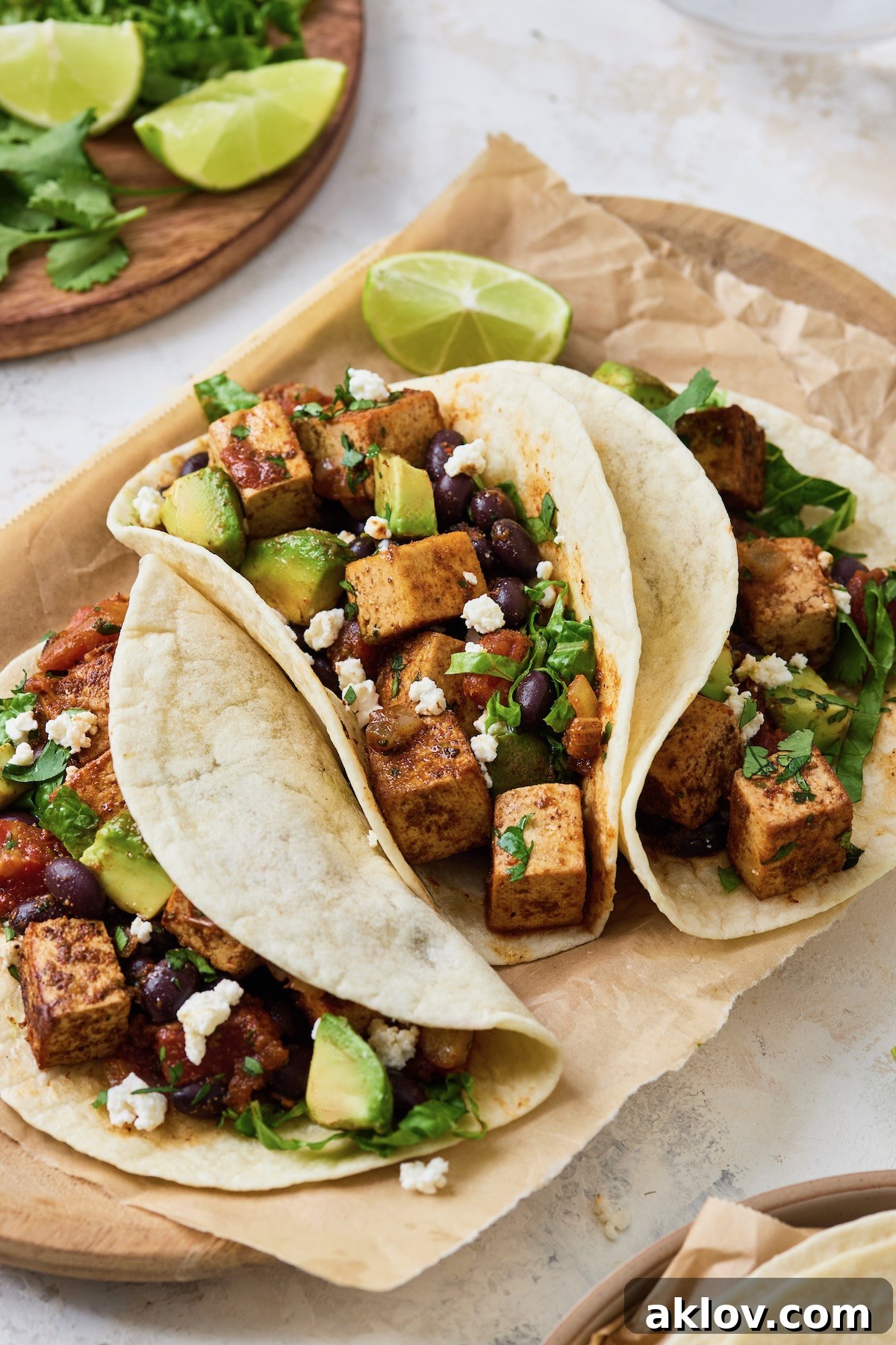 A trio of delicious Tofu Black Bean Tacos served on parchment paper on a wooden tray, ready for a flavorful meal.