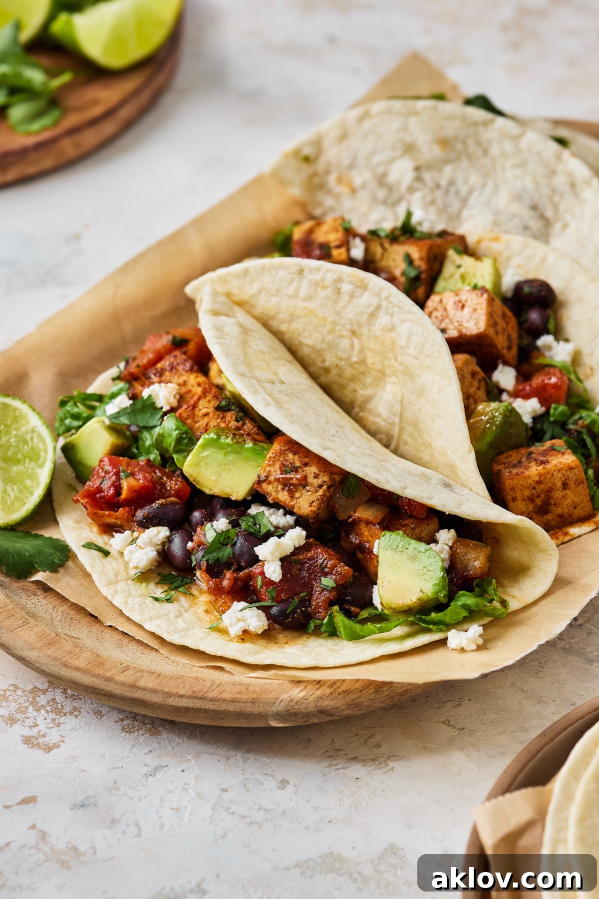 A close-up view of a single Tofu Black Bean Taco, beautifully garnished and ready to eat, resting on parchment paper.