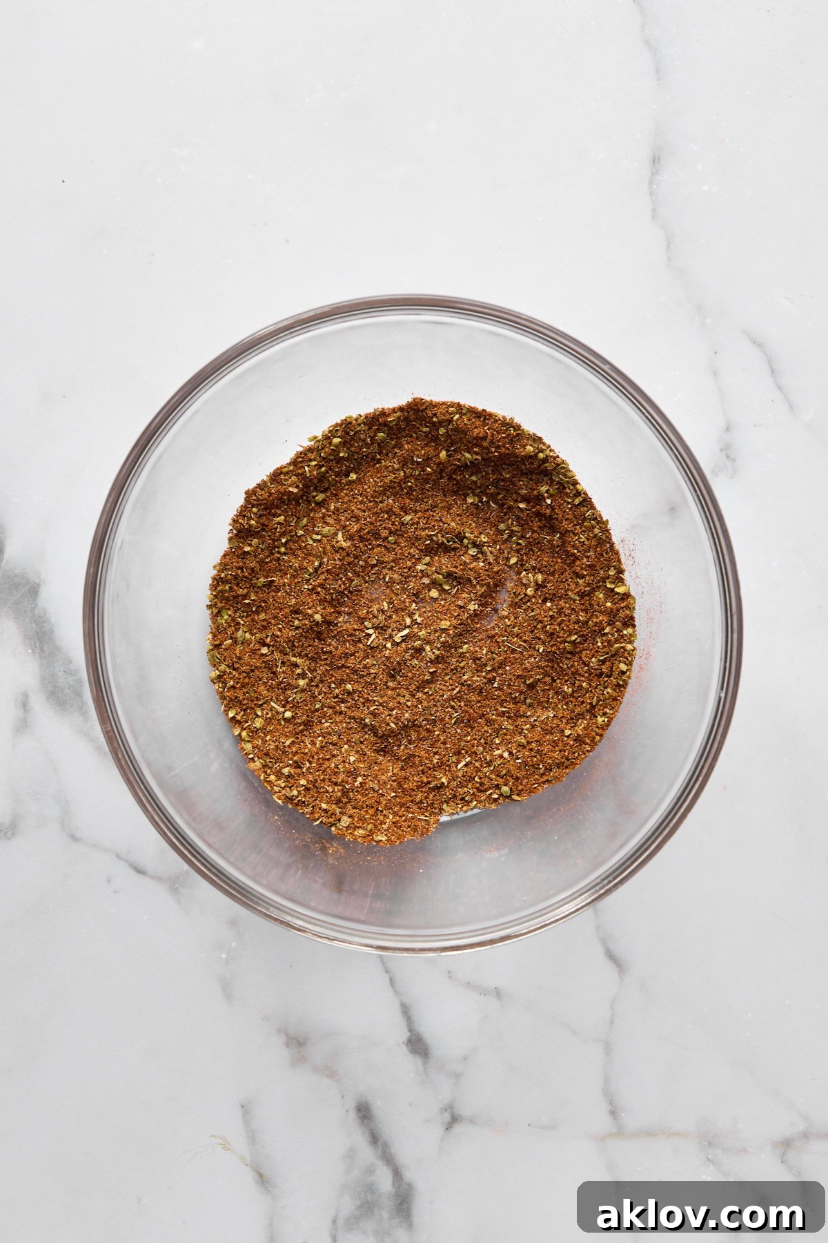 A vibrant blend of chili powder, cumin, coriander, oregano, chipotle powder, salt, and black pepper mixed in a small glass bowl.