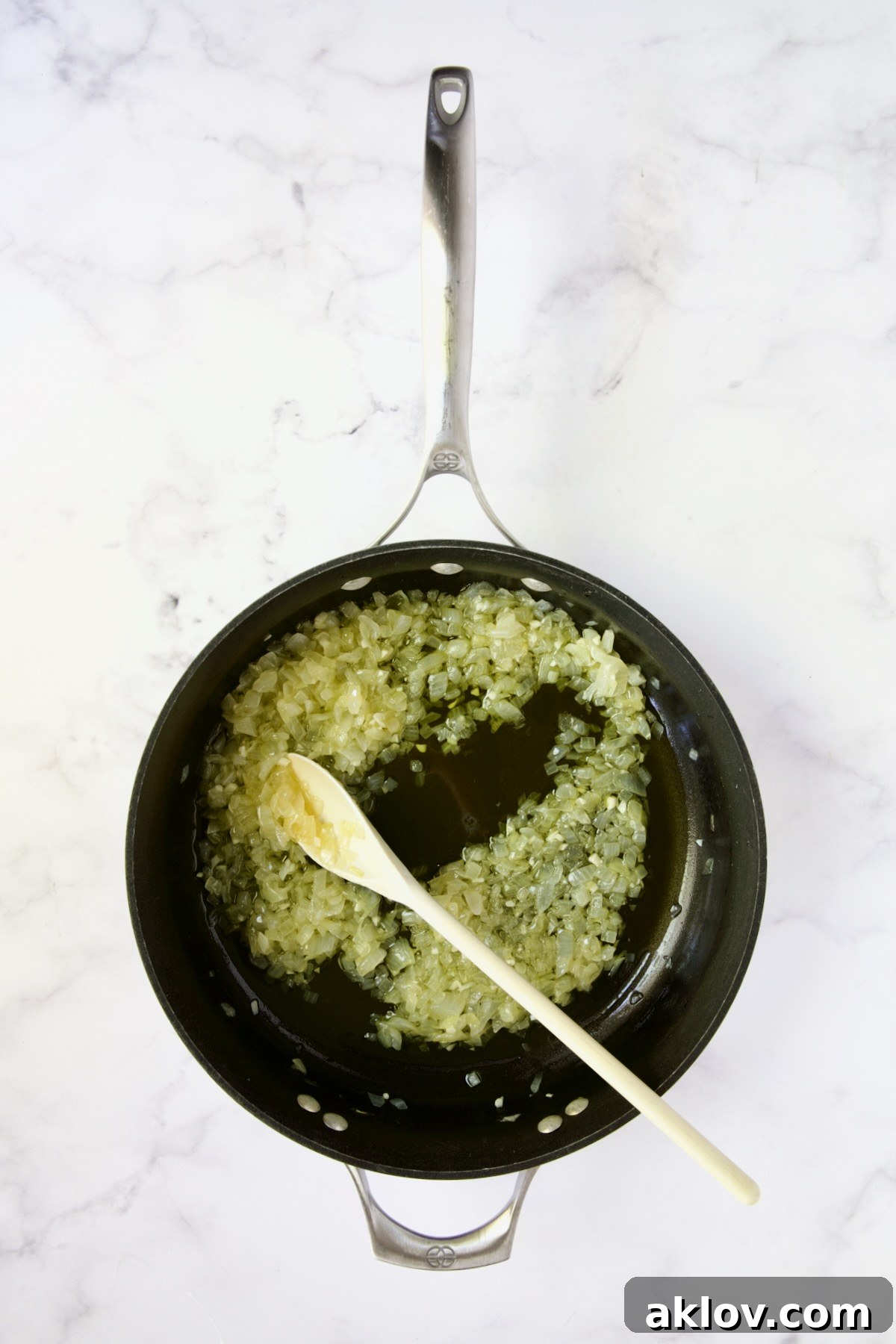 Chopped onions being sauteed in a nonstick skillet, turning translucent.