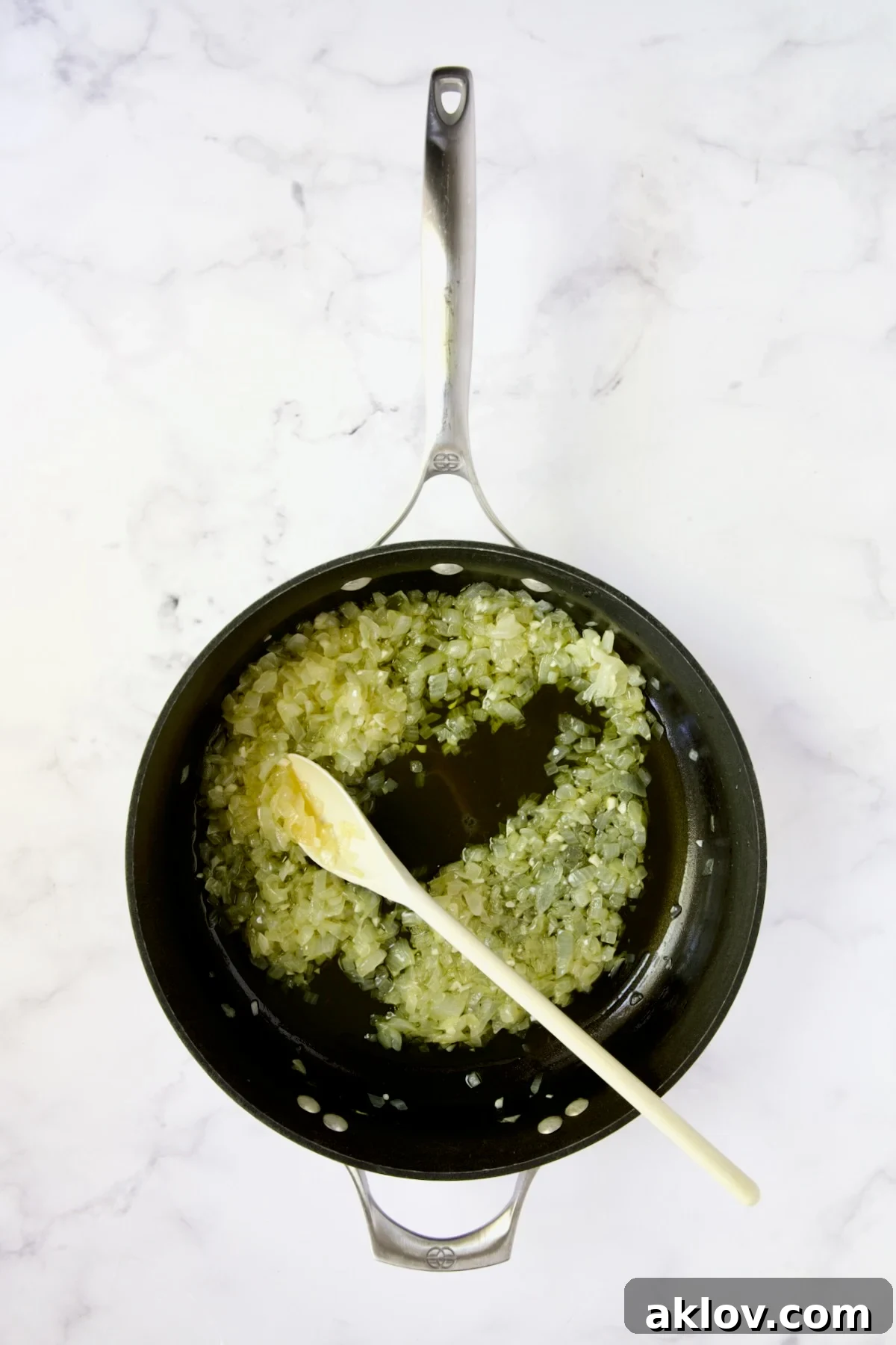 Chopped onions being sauteed in a nonstick skillet with olive oil.