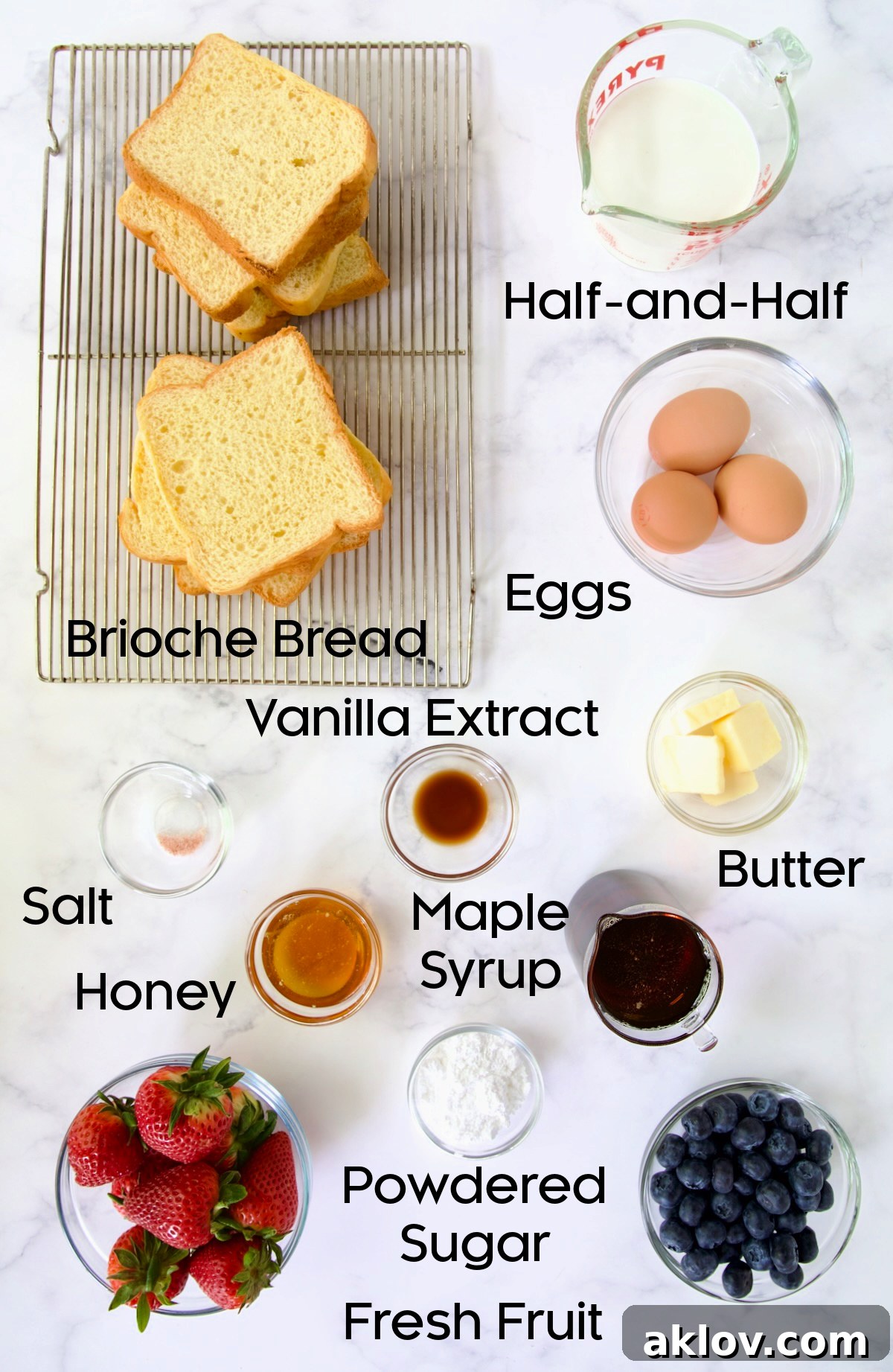Individual ingredients laid out for making Brioche French Toast, including brioche bread, eggs, half-and-half, honey, vanilla extract, and butter.