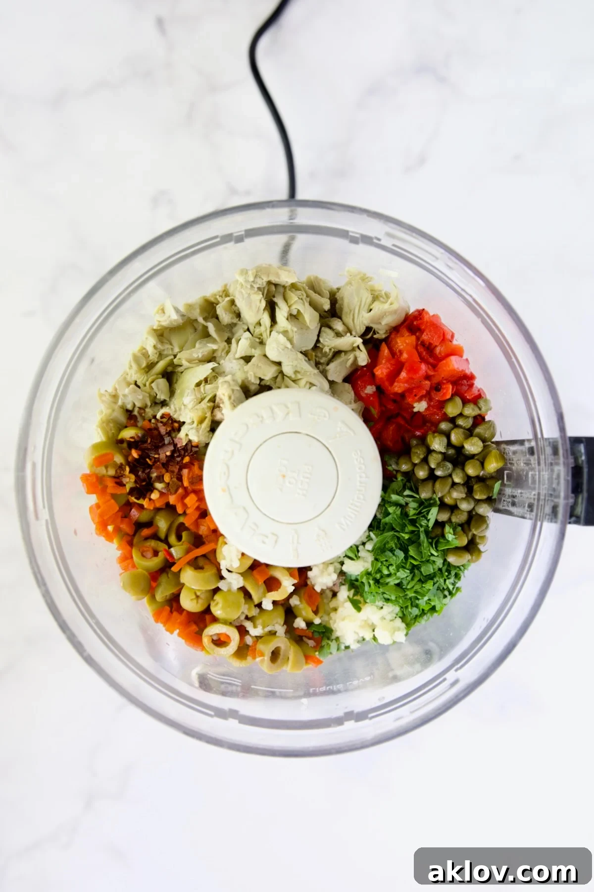 Ingredients for Artichoke Tapenade loaded into a food processor, ready for blending.