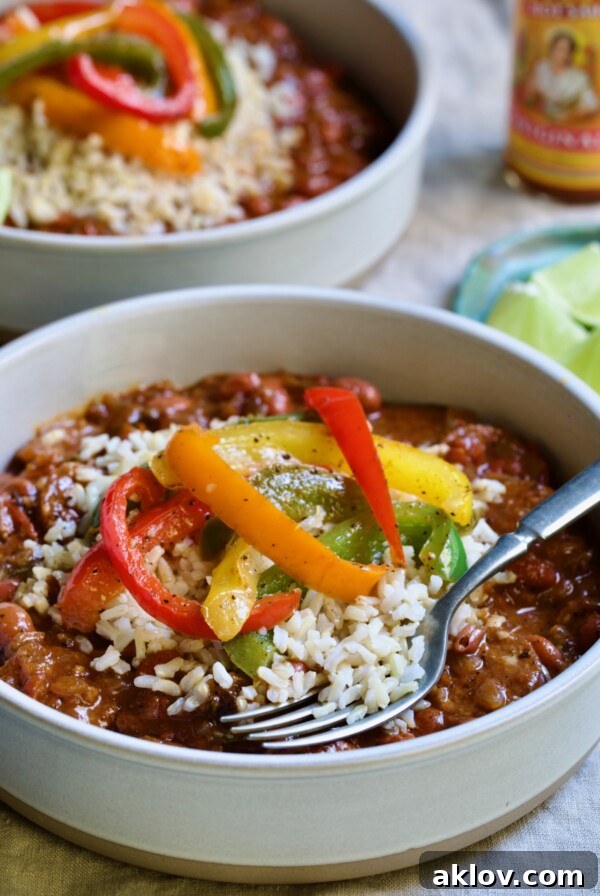 One serving of Southwestern Red Beans and Rice in a white bowl garnished with colorful sauteed bell peppers.