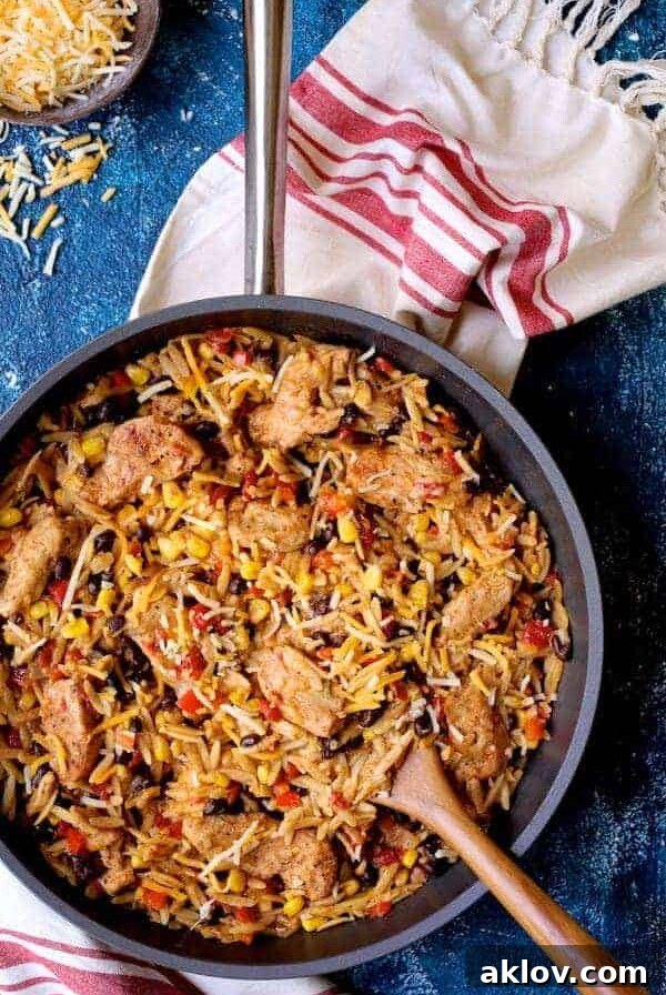 Chicken, Orzo and Black Bean Skillet in the skillet being stirred with wooden spoon.