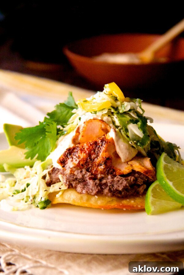Salmon and Black Bean Tostadas with Cilantro - Lime Slaw and Chipotle Crema on white plate with lime wedges.