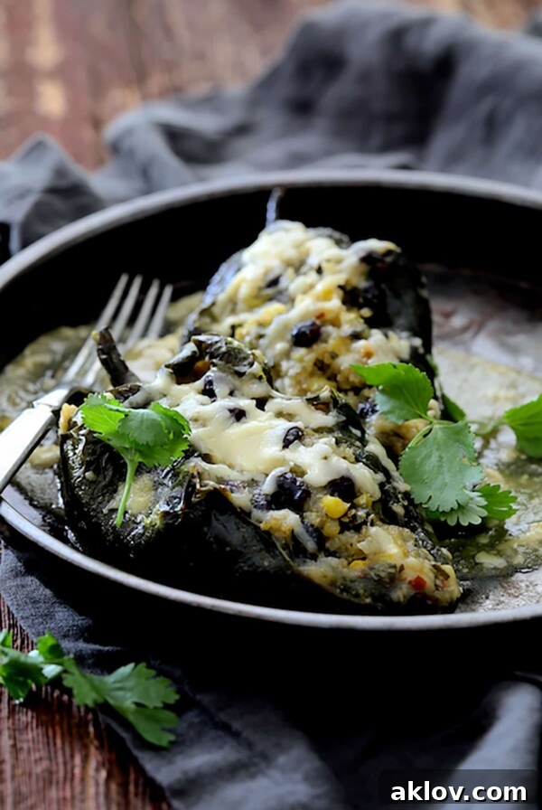 Two Quinoa Corn and Black Bean Stuffed Poblano Peppers in brown ceramic dish garnished with cilantro.