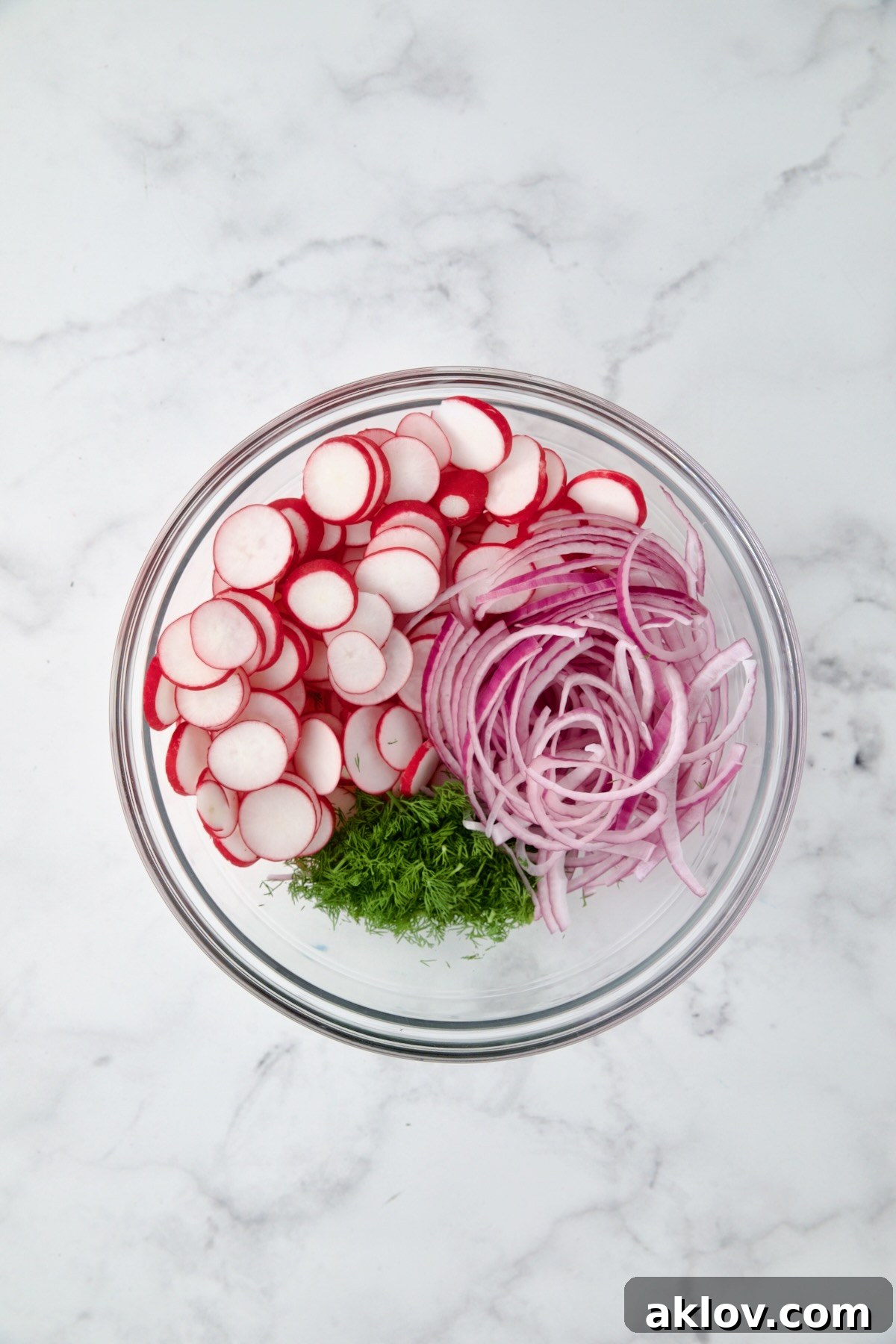 Refreshing Radish Salad 6 Radishes, red onion and dill in glass bowl.