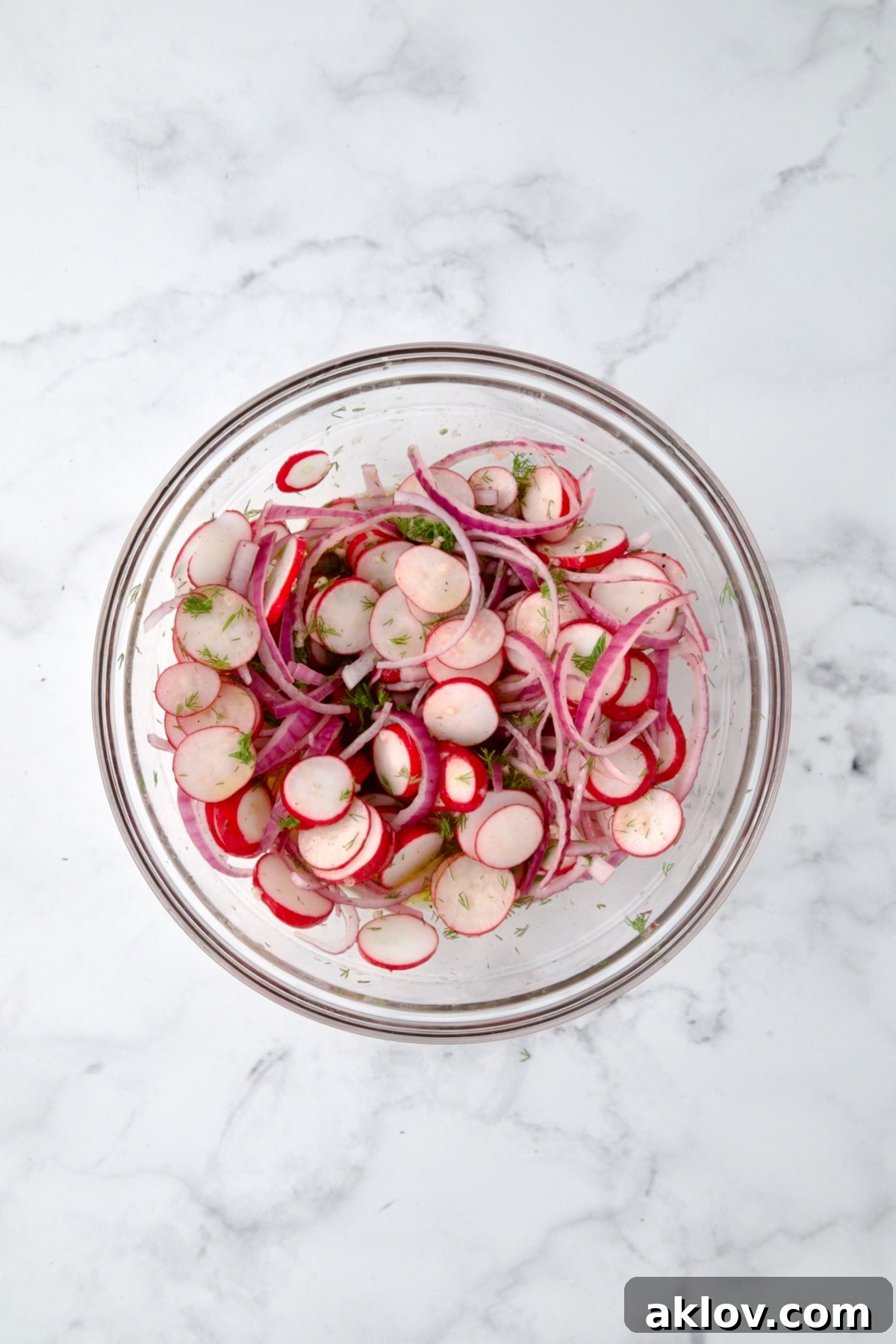 Refreshing Radish Salad 7 Radishes, red onion and dill mixed together in glass bowl.