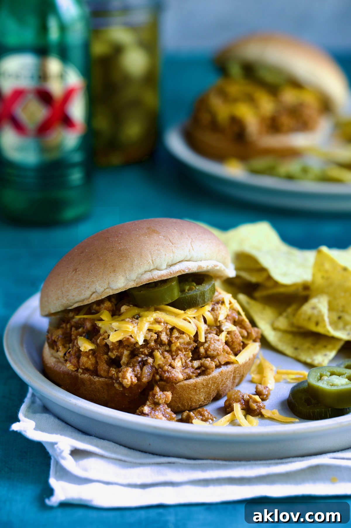 Chicken Sloppy Joes on plate with tortilla chips and jalapeno slices.