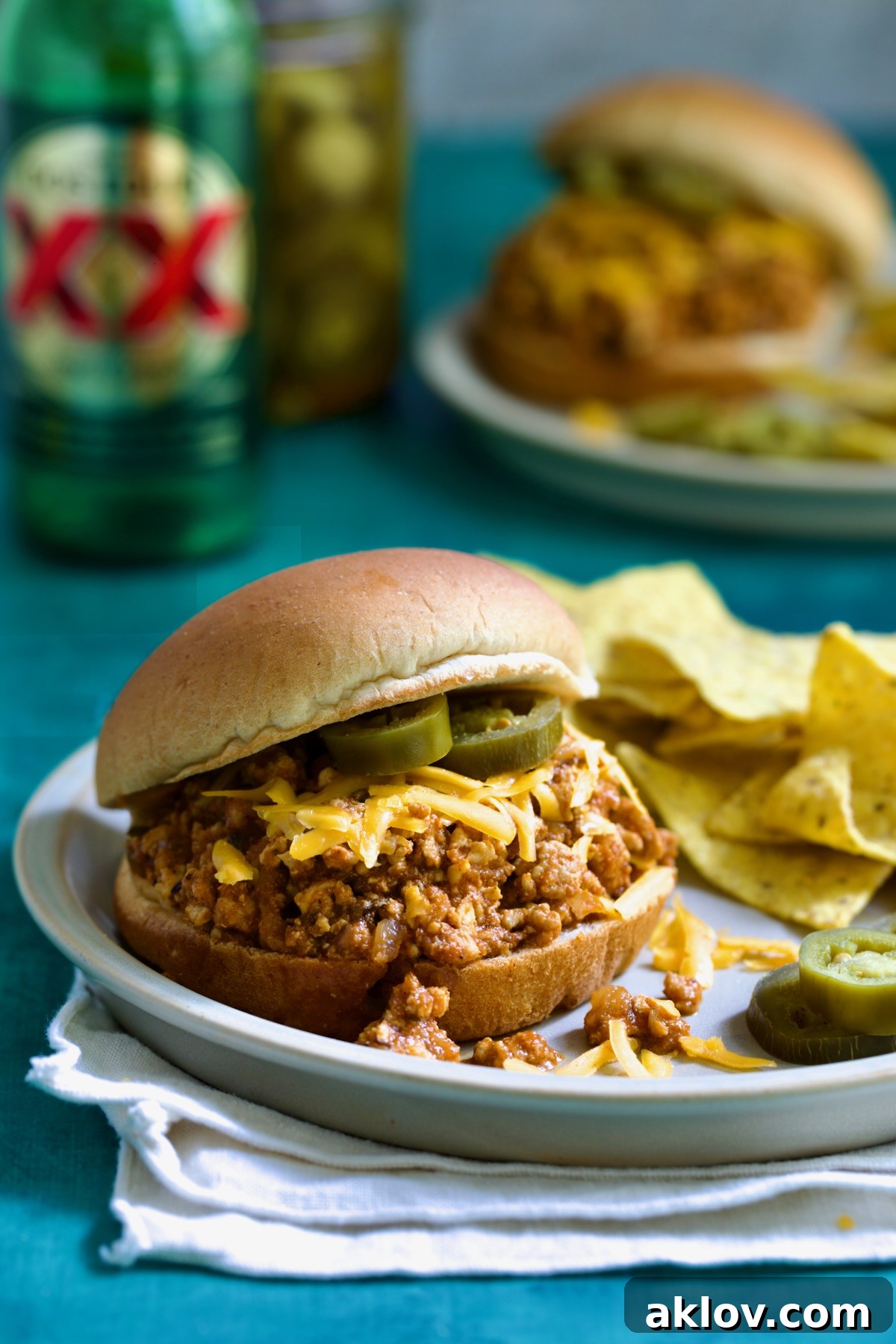 Chicken Sloppy Joes on plate with tortilla chips and jalapeno slices.
