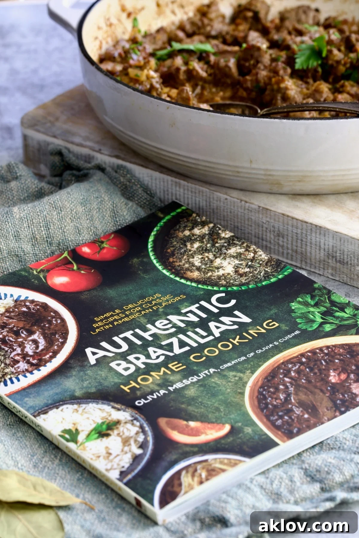 Hearty Beer Braised Beef Tips 5 A beautifully composed shot showing Olivia Mesquita's 'Authentic Brazilian Home Cooking' cookbook open to a recipe page, with a bowl of savory beef tips nearby.