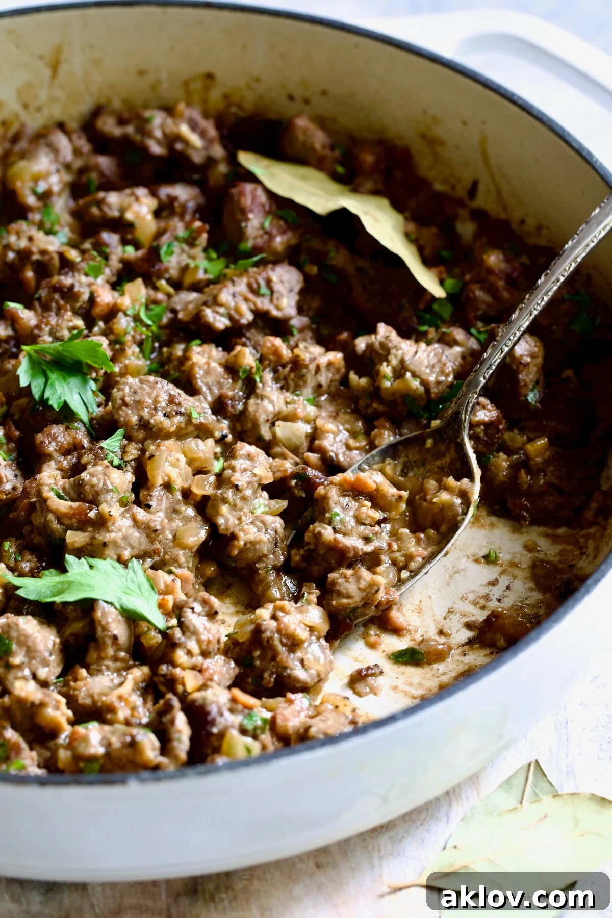 Hearty Beer Braised Beef Tips 7 A vibrant close-up of tender beef tips simmering in a savory beer sauce within a white enamel cast iron skillet, ready to be served.