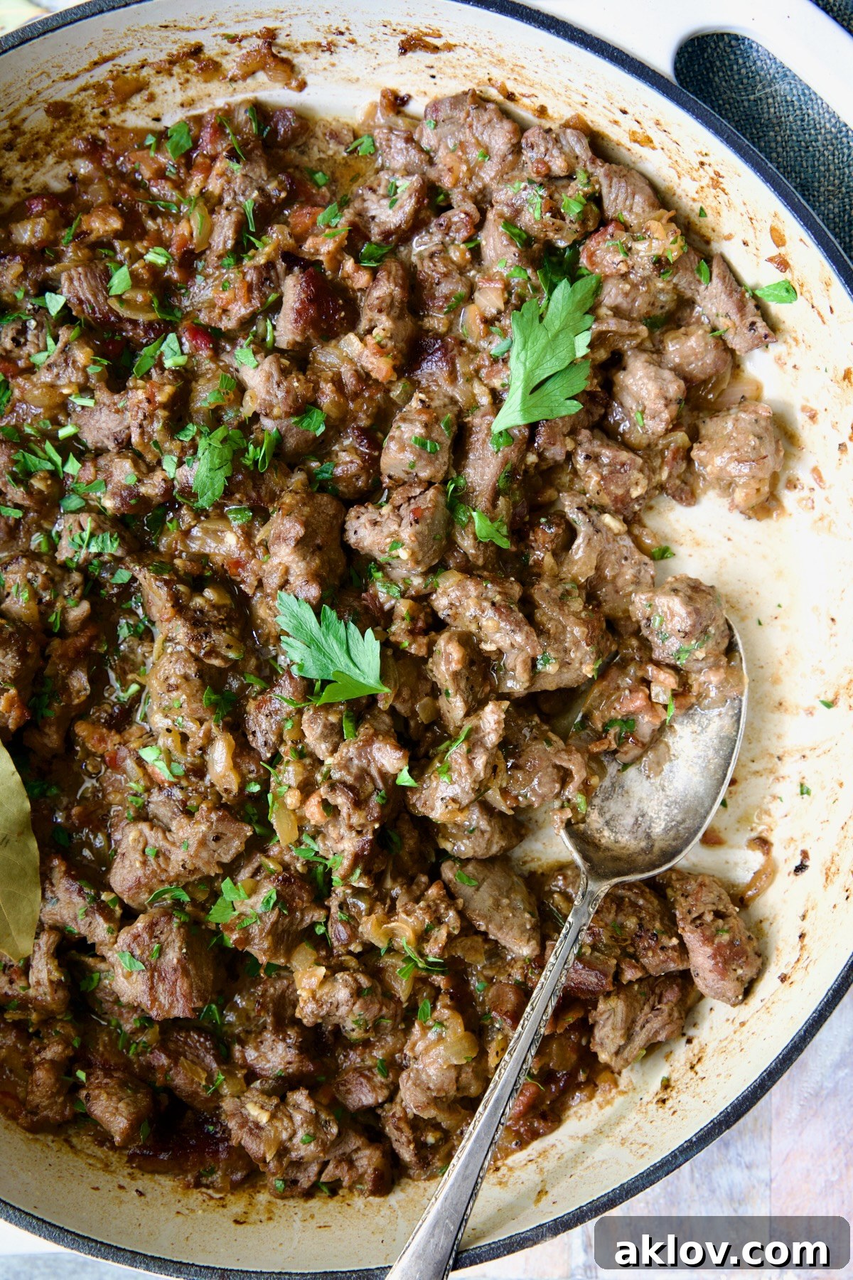 A tempting serving of Beef Tips in Beer Sauce (Picadinho na Cerveja) in a white enamel cast iron skillet, garnished with fresh parsley.