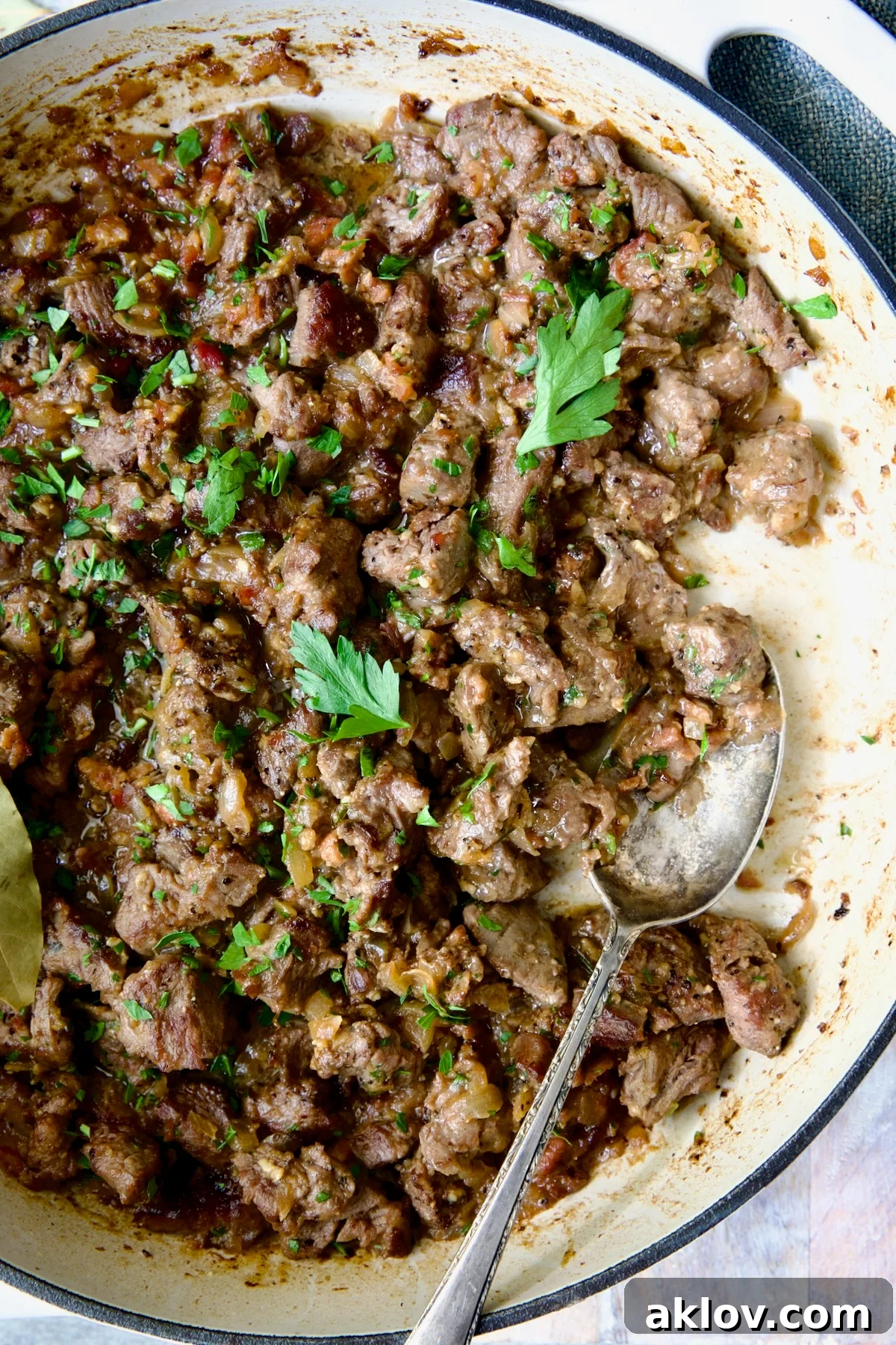 Hearty Beer Braised Beef Tips 8 A comforting serving of Beef Tips in Beer Sauce (Picadinho) presented in a white enamel cast iron skillet, garnished with fresh herbs, ready to be enjoyed.