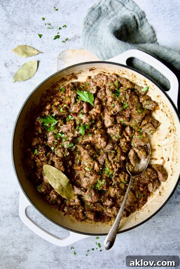 Beef Tips in Beer Sauce in white enamel cast iron skillet.