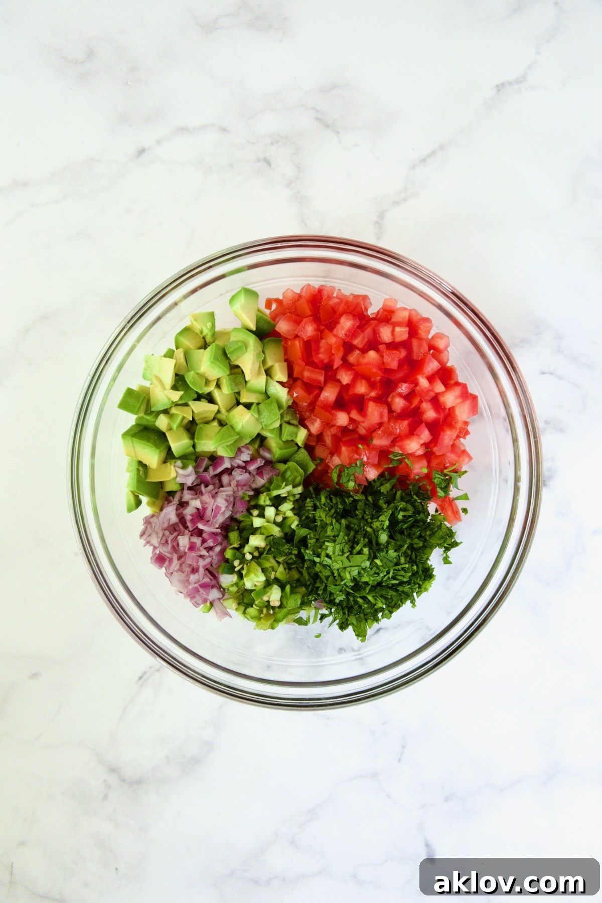 Glass bowl of fresh ingredients for salsa before mixing.