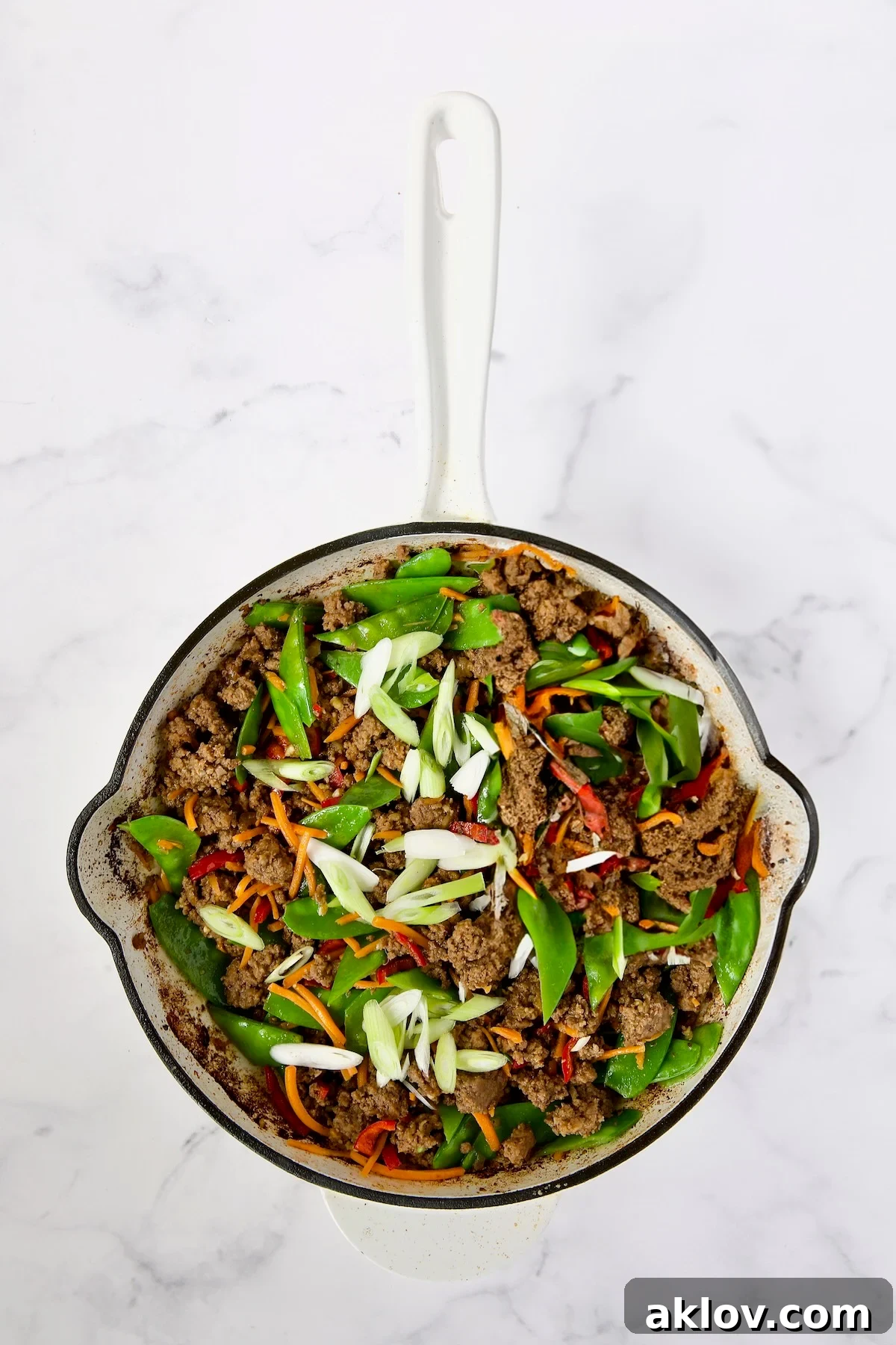 Spicy Thai Basil Beef Stir-fry 11 The stir-fry progresses, with cooked ground beef, Fresno chiles, shredded carrots, snow peas, and sliced scallions combined in the skillet, vibrant and aromatic.