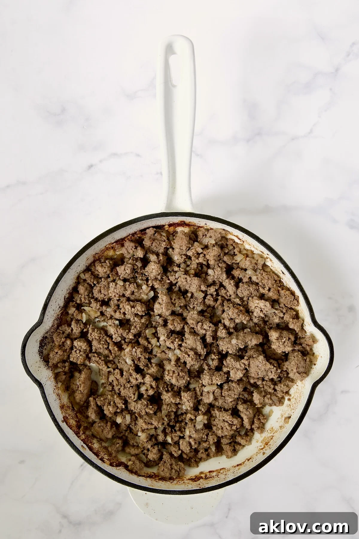 Spicy Thai Basil Beef Stir-fry 7 Perfectly browned and crumbled ground beef in a white enamel cast iron skillet, ready for the next step of adding spices.