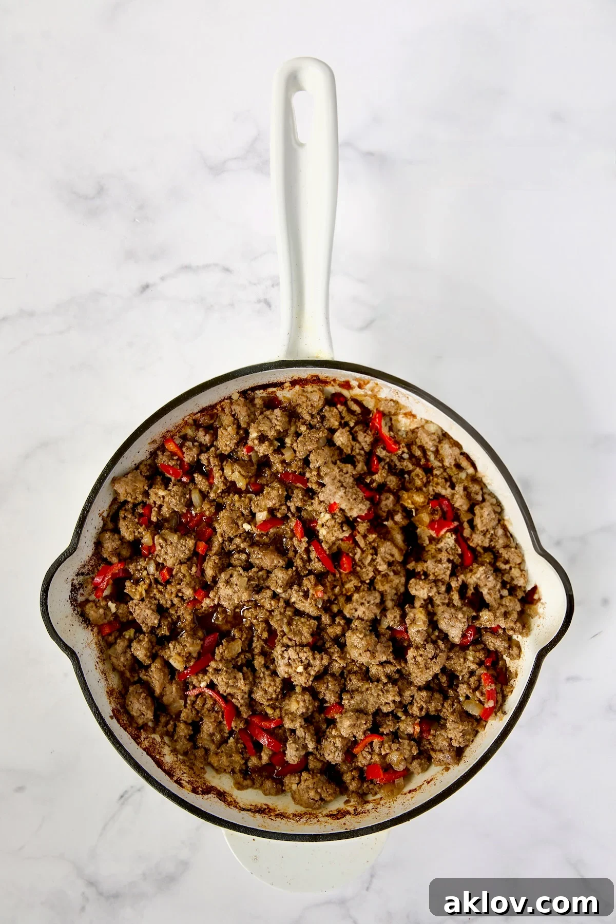 Spicy Thai Basil Beef Stir-fry 9 A closer view of cooked ground beef mixed with vibrant Fresno chiles in a white enamel cast iron skillet, showing a perfectly seared texture.