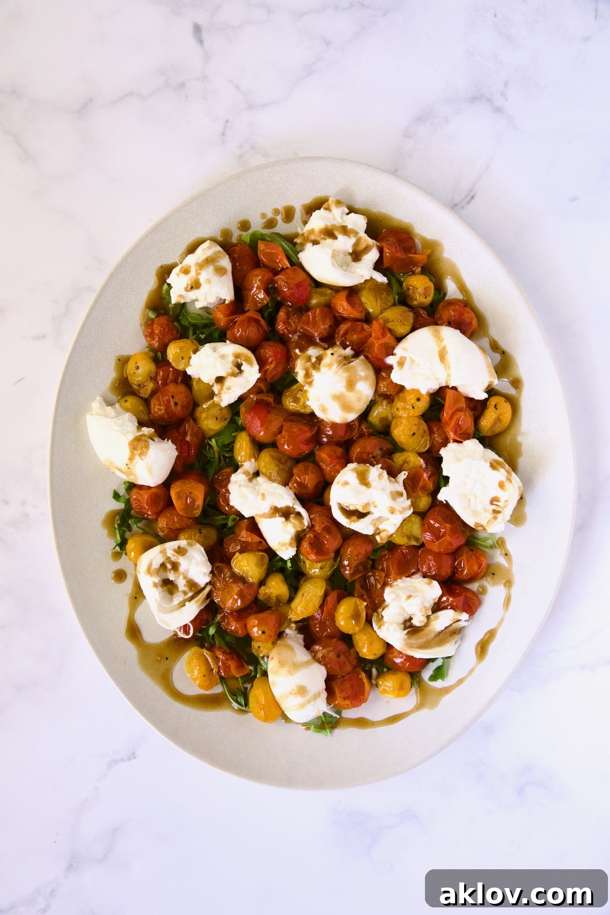 Creamy Burrata Caprese with Sweet Roasted Cherry Tomatoes 11 The fully assembled Burrata Caprese Salad with roasted cherry tomatoes, arugula, and burrata, glistening with a drizzle of balsamic vinaigrette.
