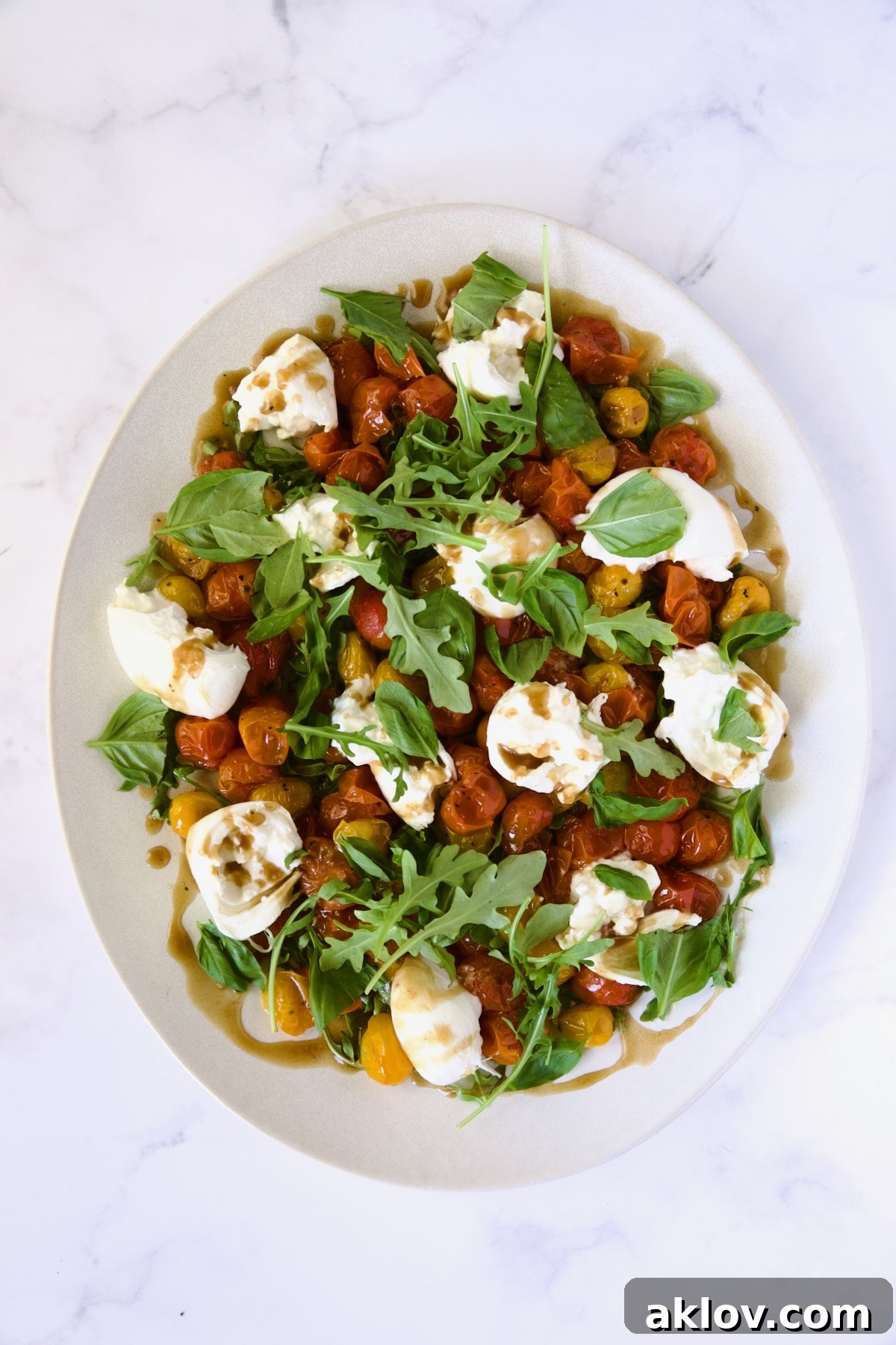 Creamy Burrata Caprese with Sweet Roasted Cherry Tomatoes 12 Roasted Cherry Tomato Burrata Caprese Salad on white oval platter.