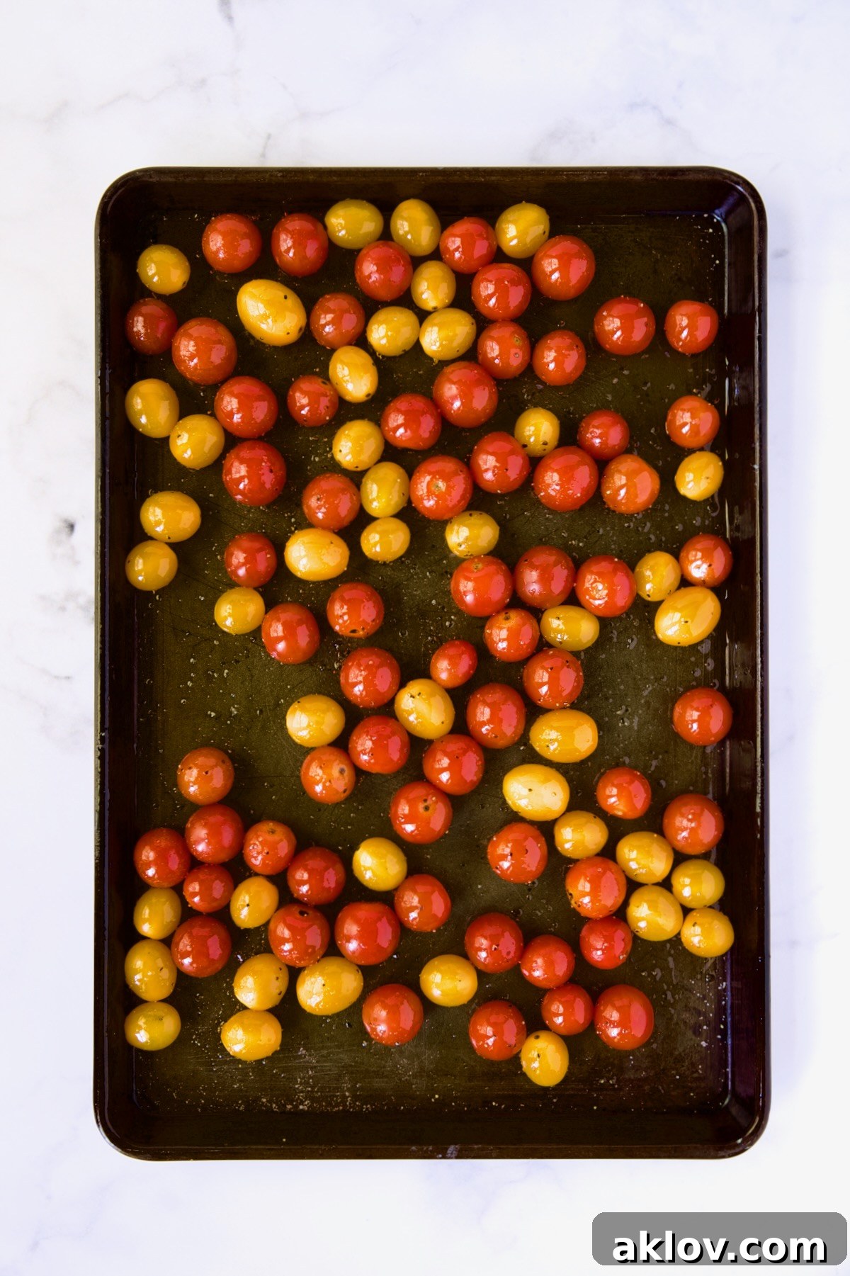 Creamy Burrata Caprese with Sweet Roasted Cherry Tomatoes 6 Red and yellow cherry tomatoes on a rimmed baking sheet before being roasted, lightly seasoned with olive oil, salt, and pepper.